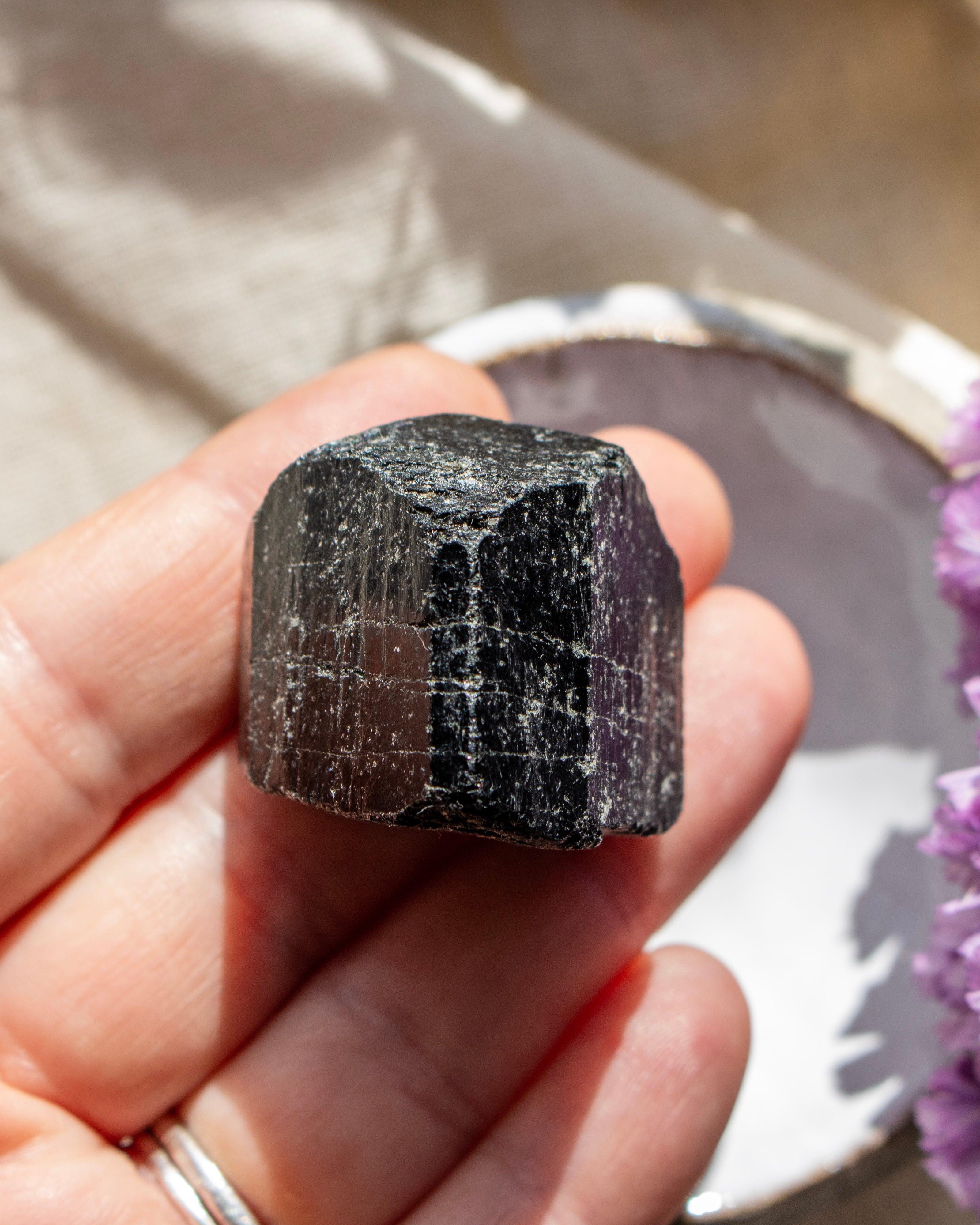 Hand holding a black crystal with a blurred background