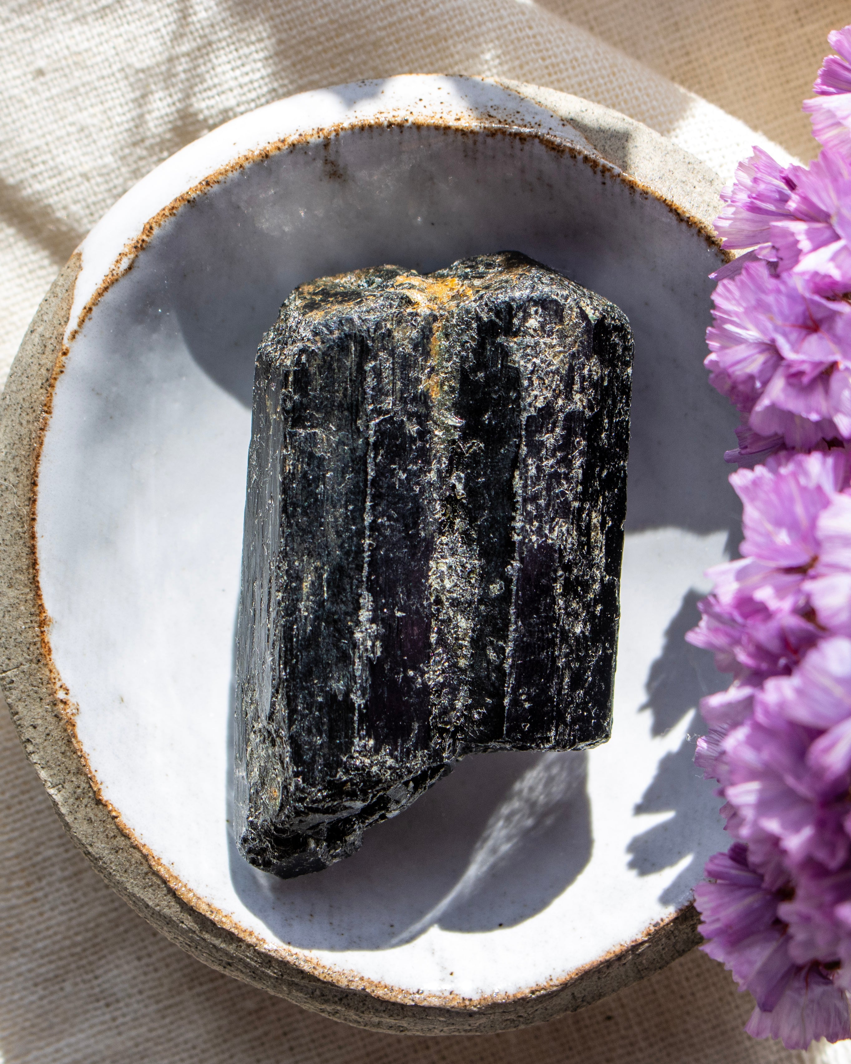 Black crystal on a white plate with purple flowers