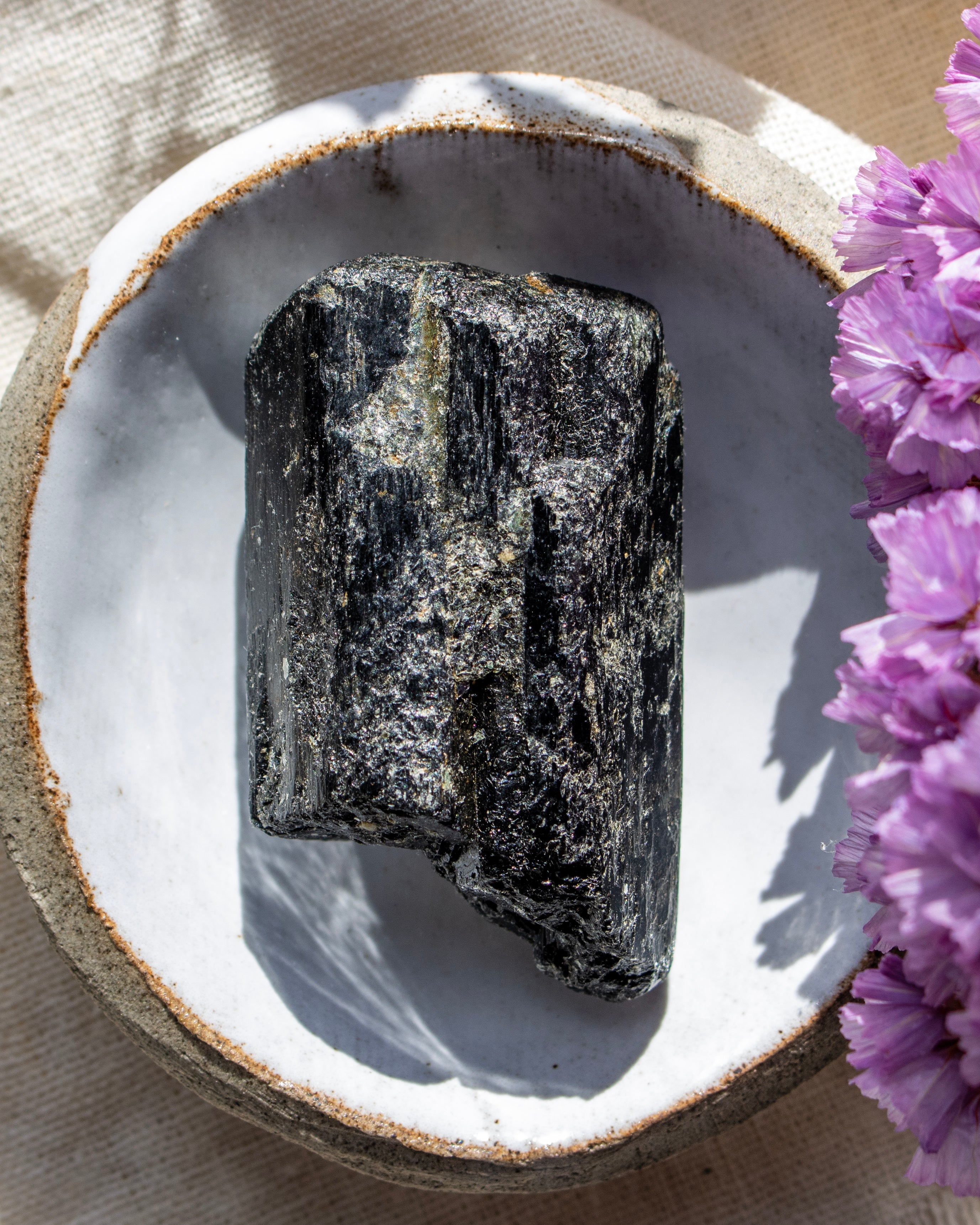 Raw crystal on a white plate with purple flowers