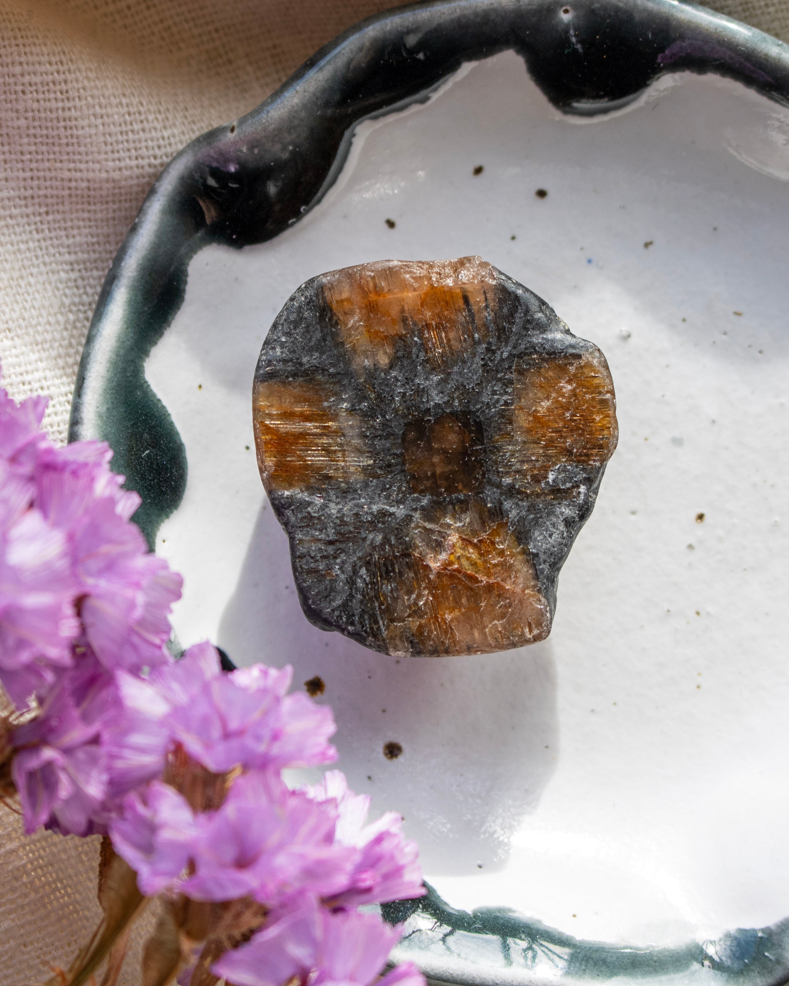 Brown stone on a white ceramic plate with purple flowers