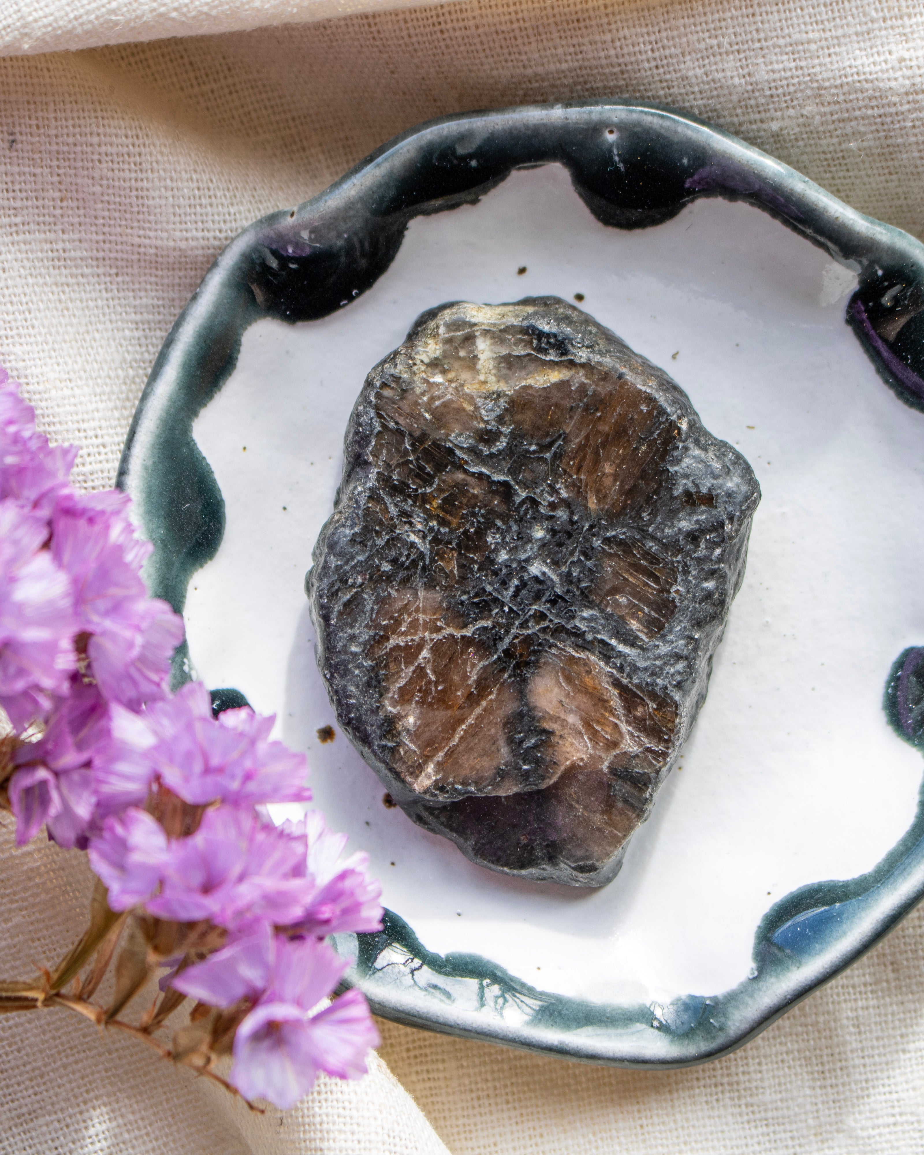 Mineral sample on a decorative plate with purple flowers