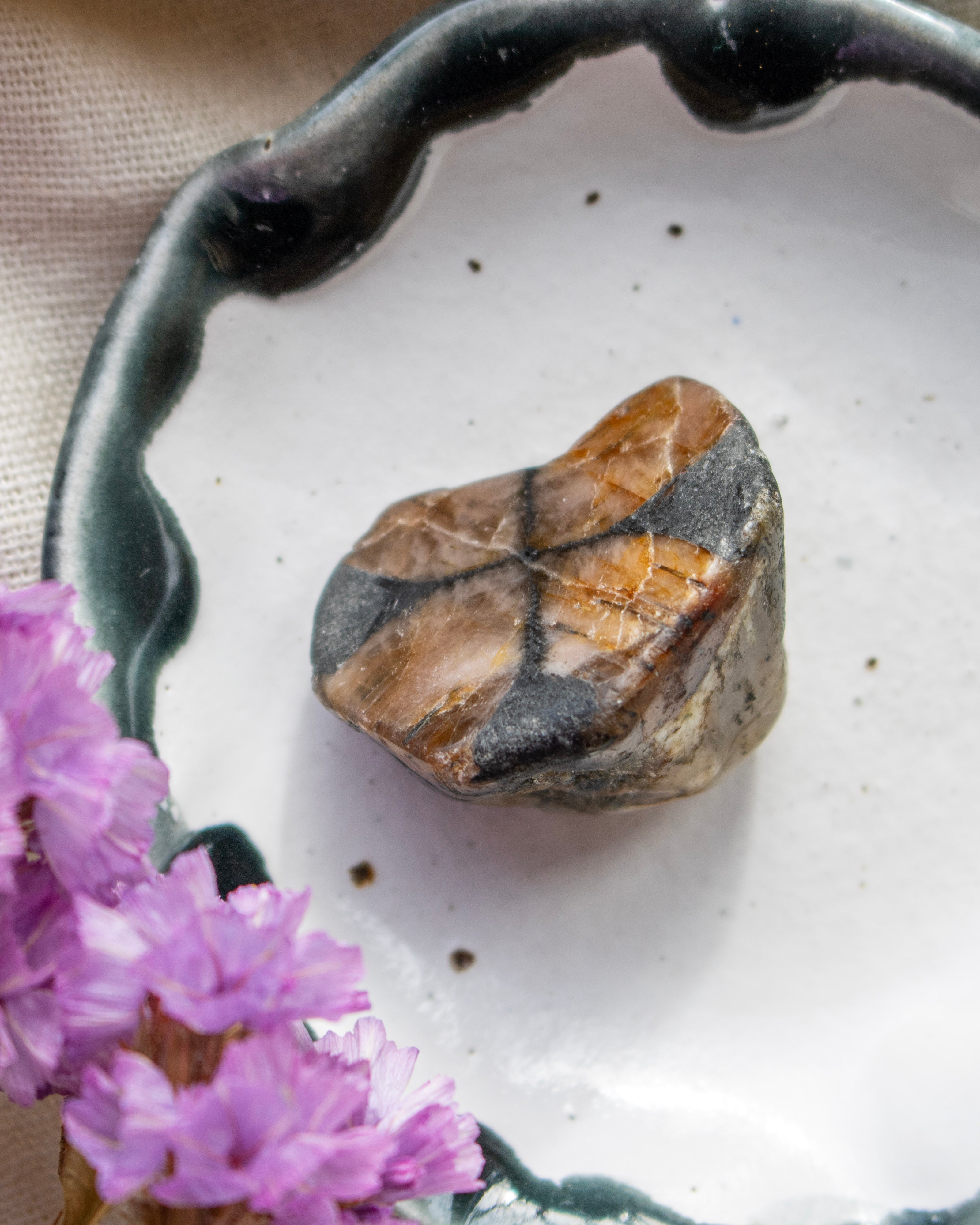 Raw stone on a white ceramic dish with purple flowers