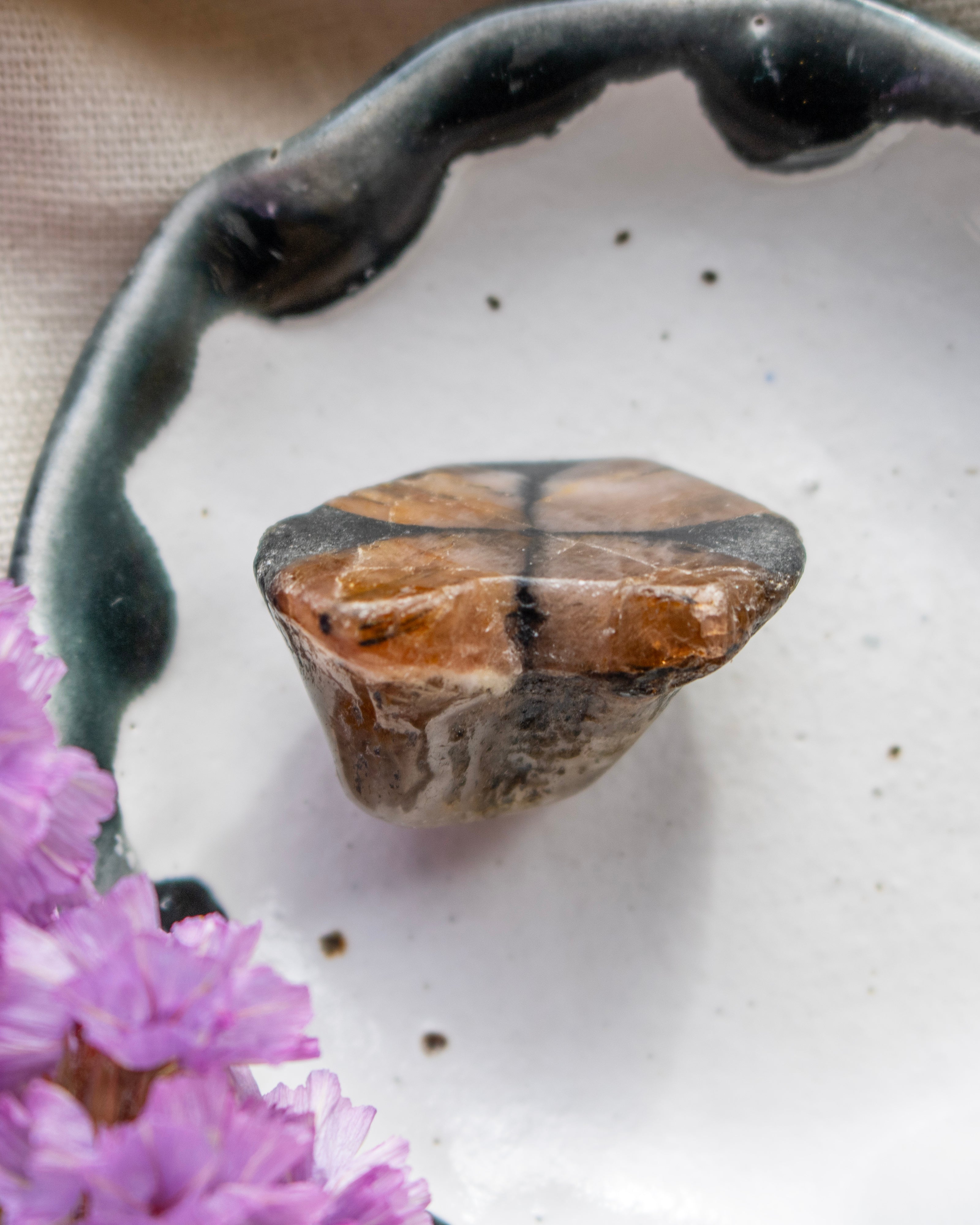 Polished stone on a textured white surface with purple flowers