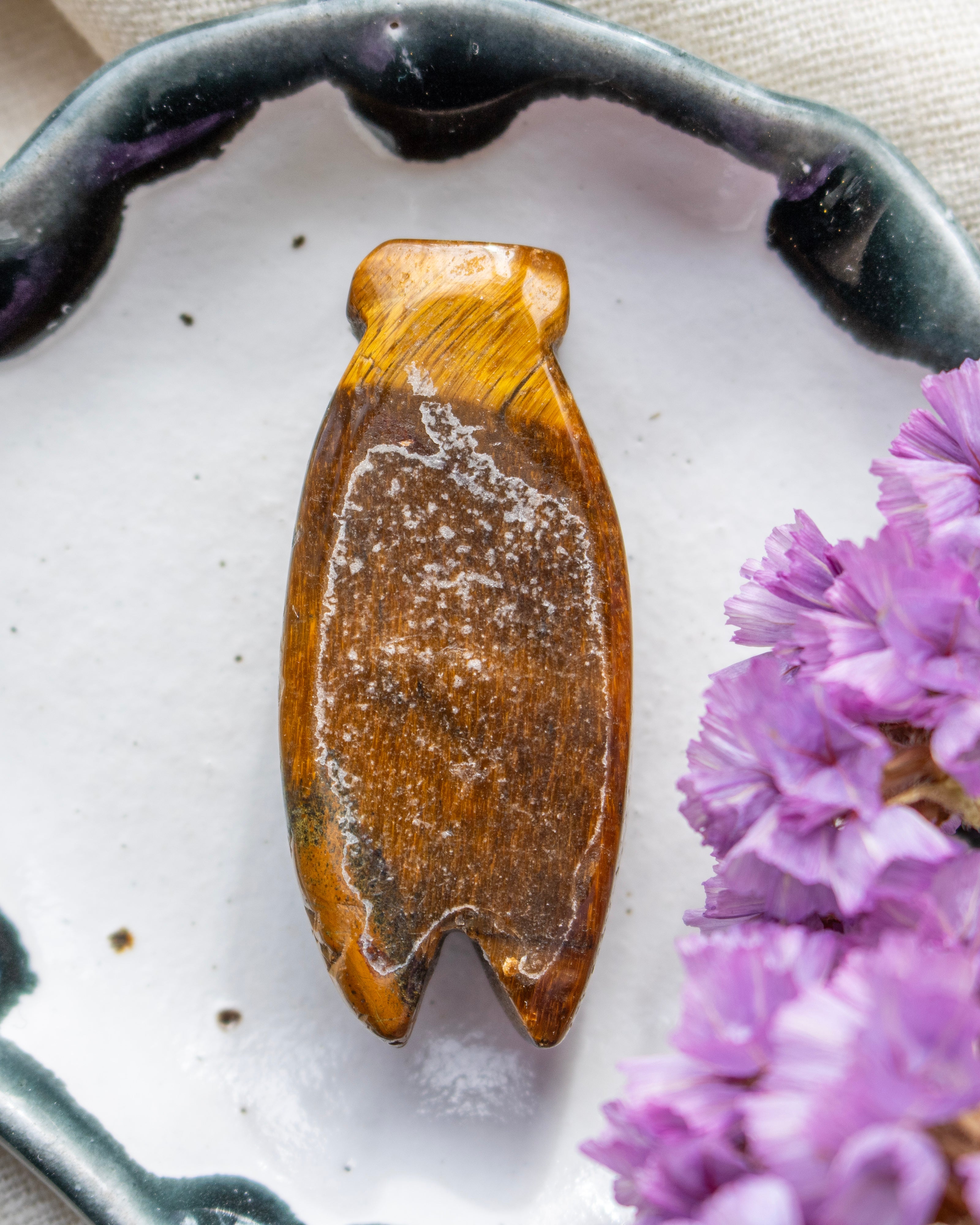 Brown stone with white specks on a white surface with purple flowers