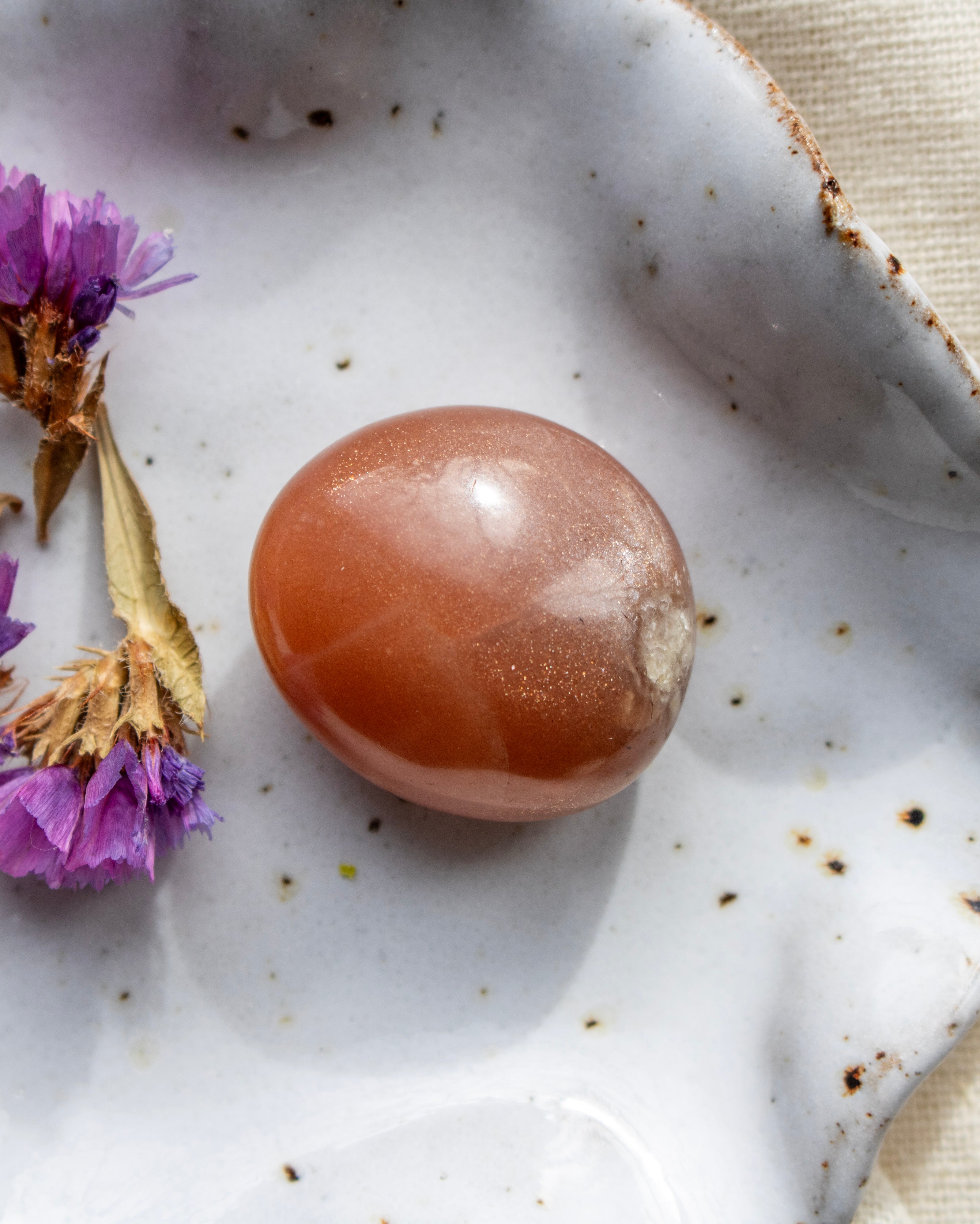 Brown stone on a textured white surface with purple flowers