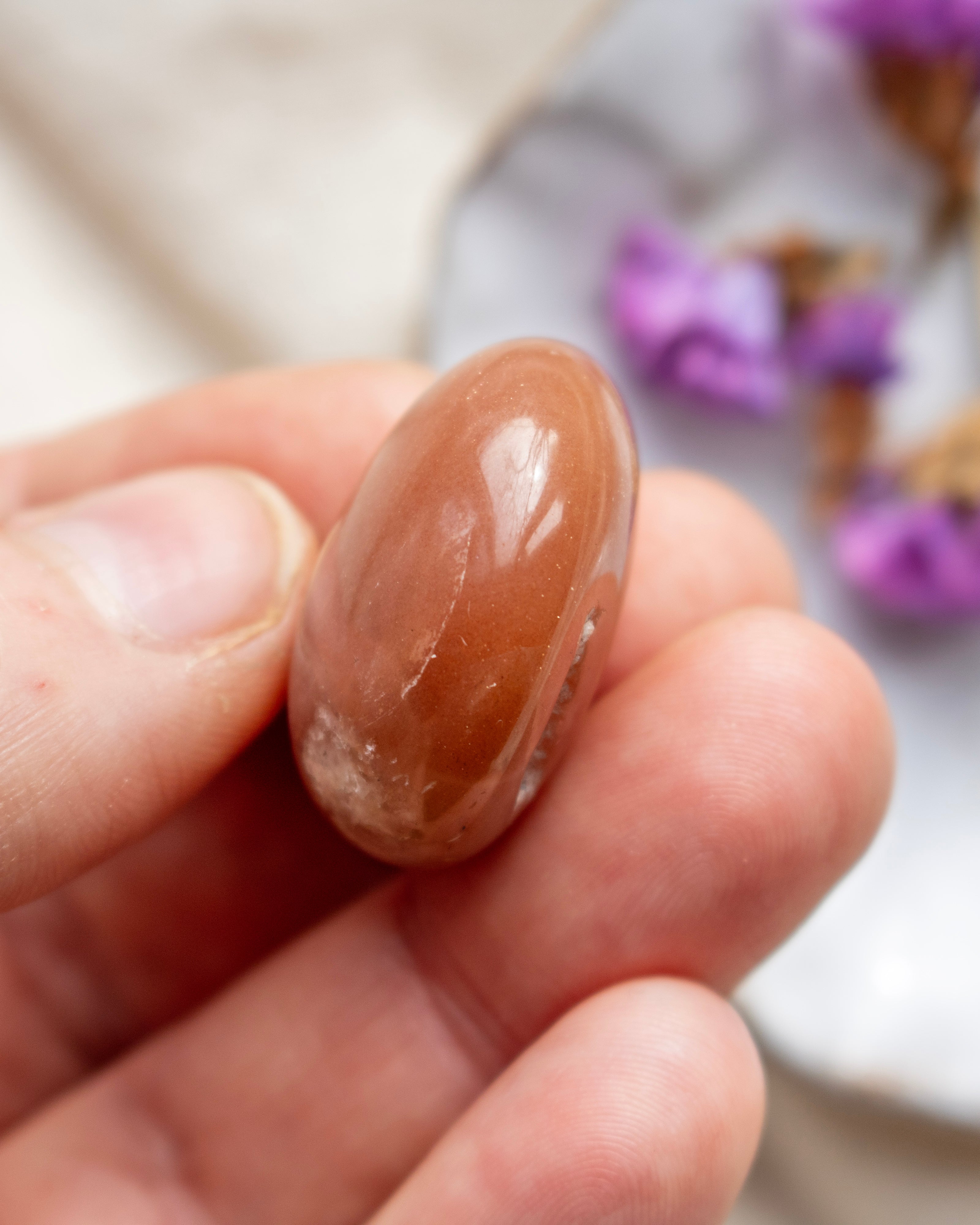 Hand holding a brown stone with a blurred background