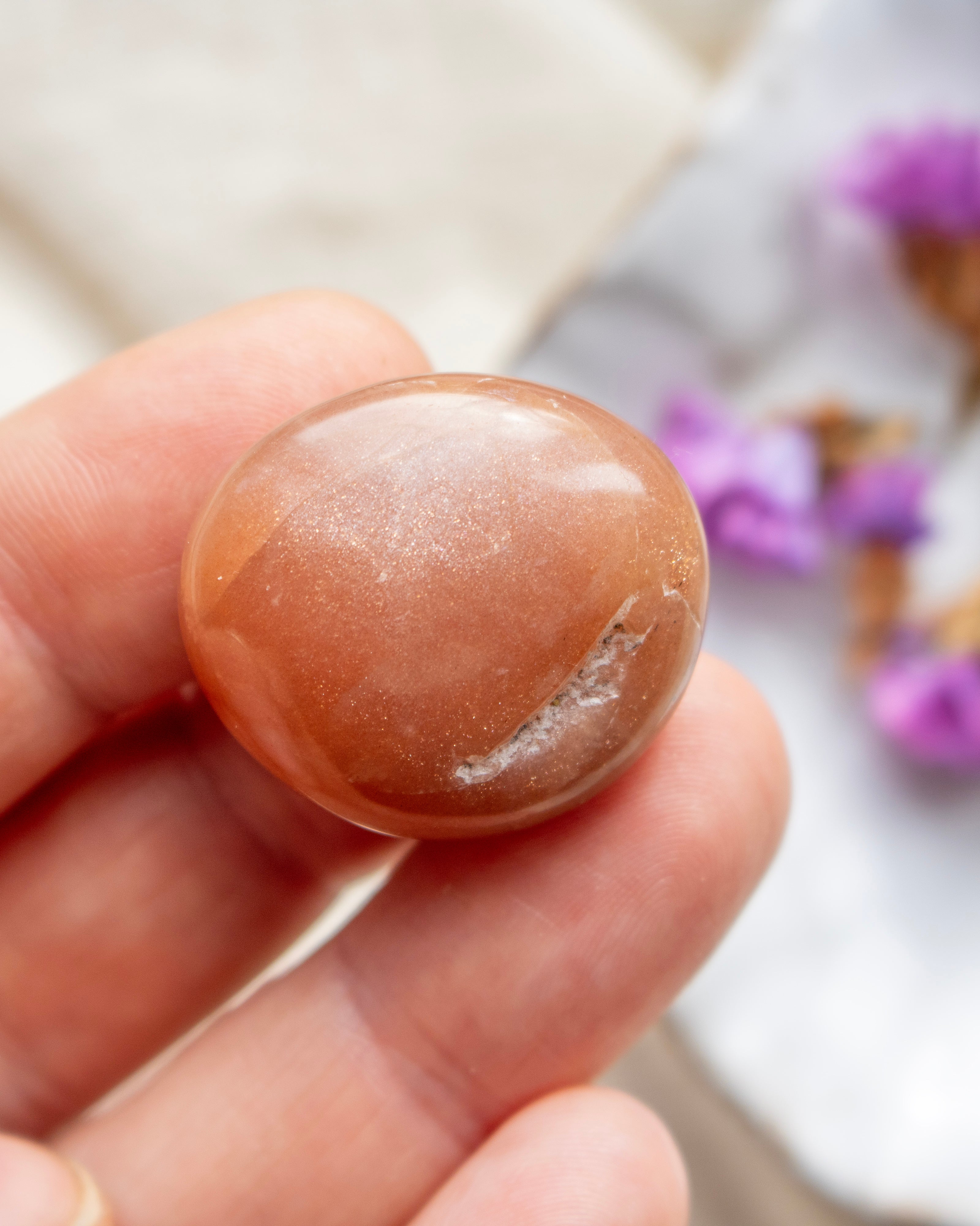Round brown stone held in a hand with a blurred background