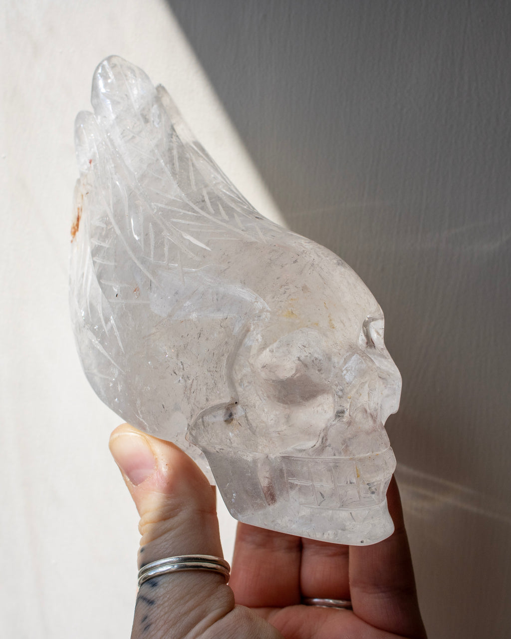 Crystal skull held in a hand against a neutral background