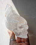 Crystal skull held in a hand against a neutral background