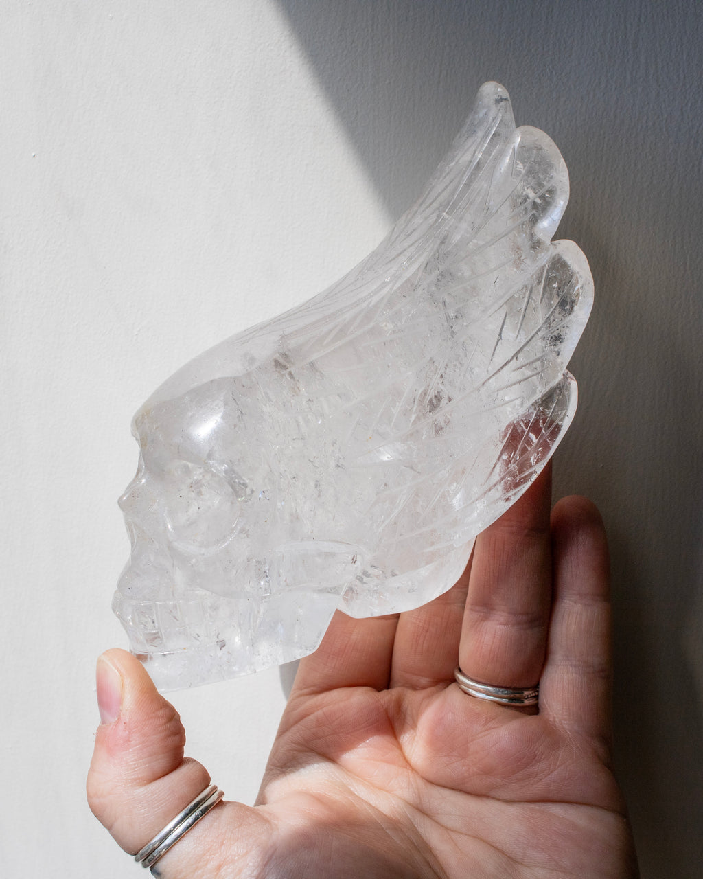 Clear crystal object held in a hand against a neutral background