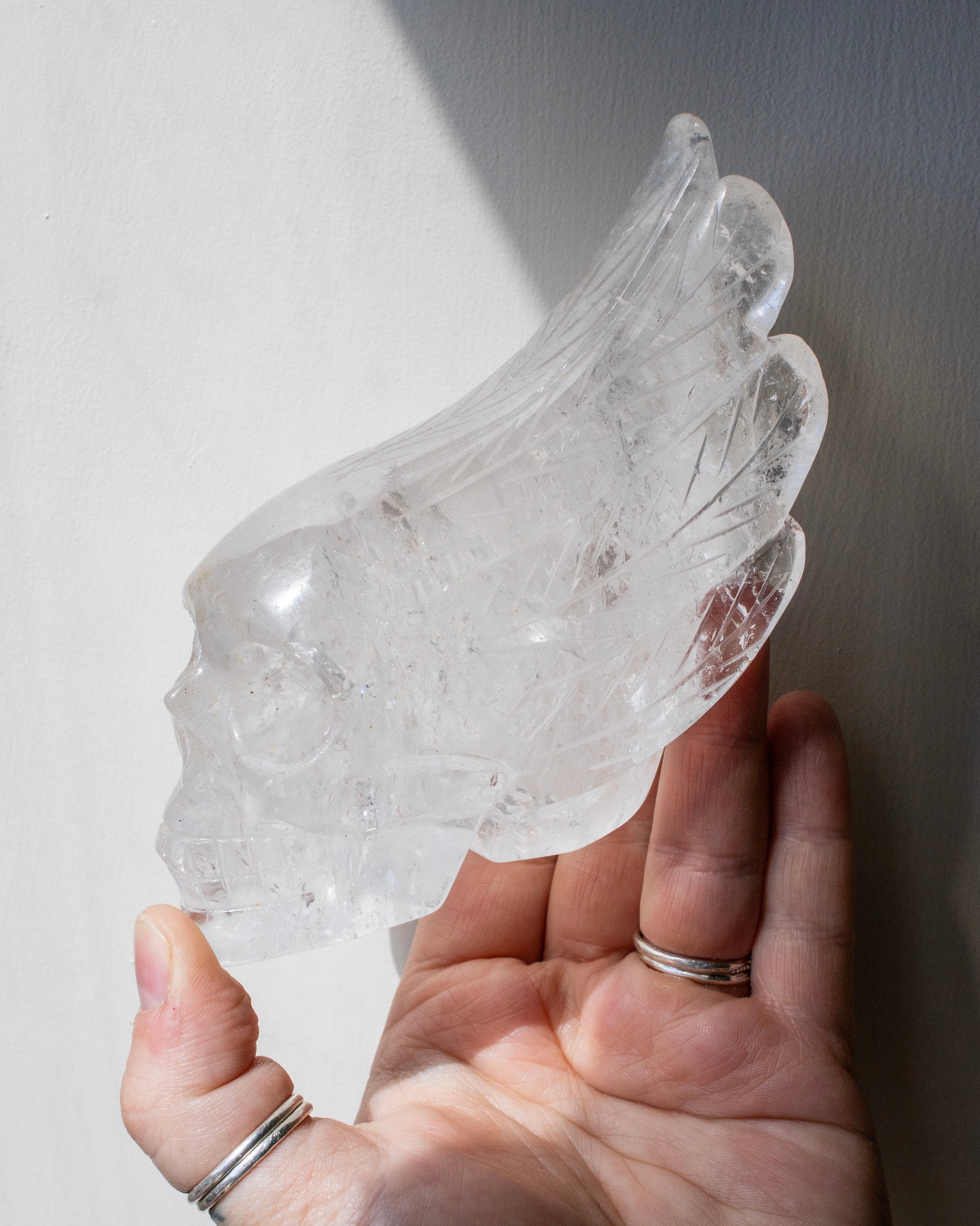 Clear crystal object held in a hand against a neutral background