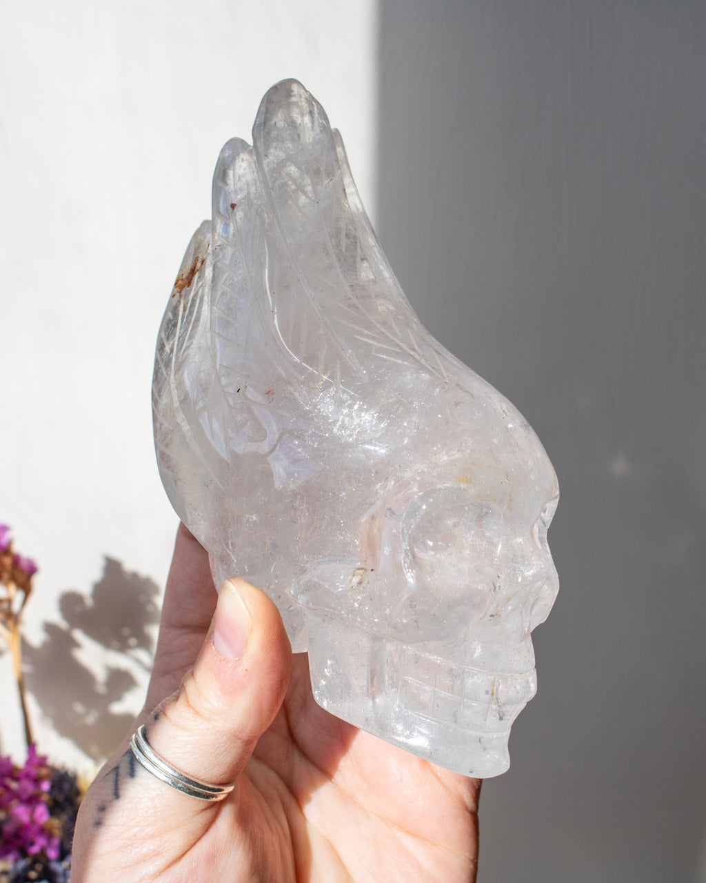 Clear crystal sculpture of a face held by a hand against a neutral background