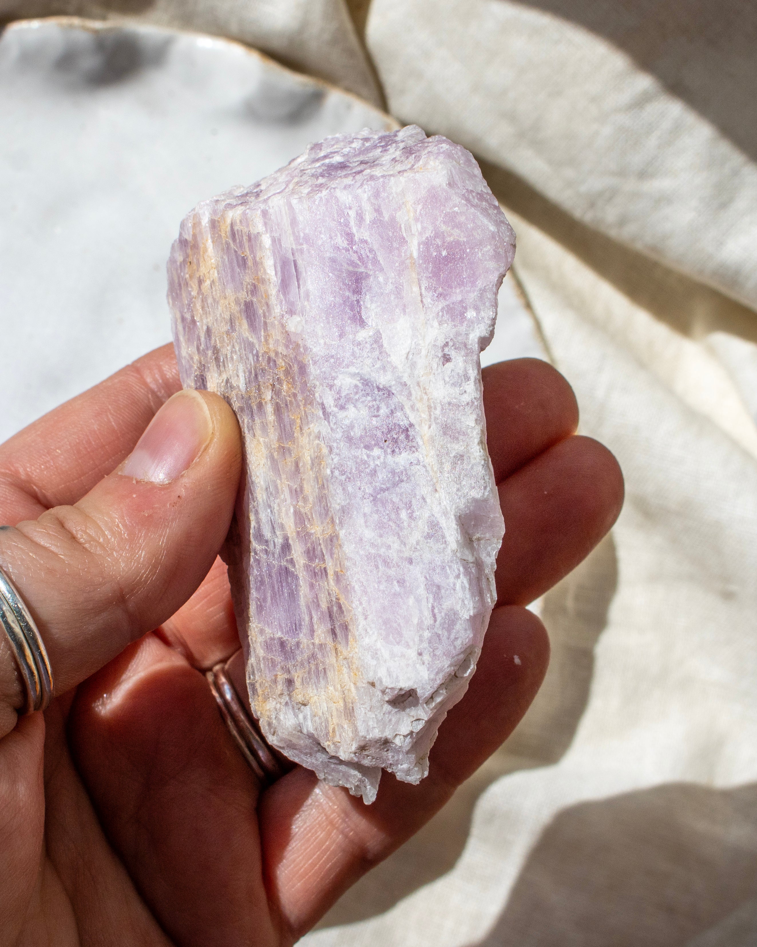 Hand holding a large purple crystal against a neutral background