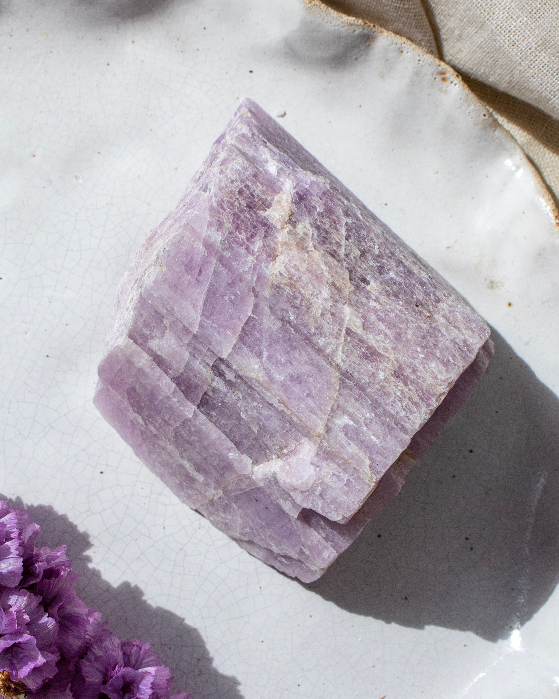 Purple crystal on a white surface with a beige cloth in the background