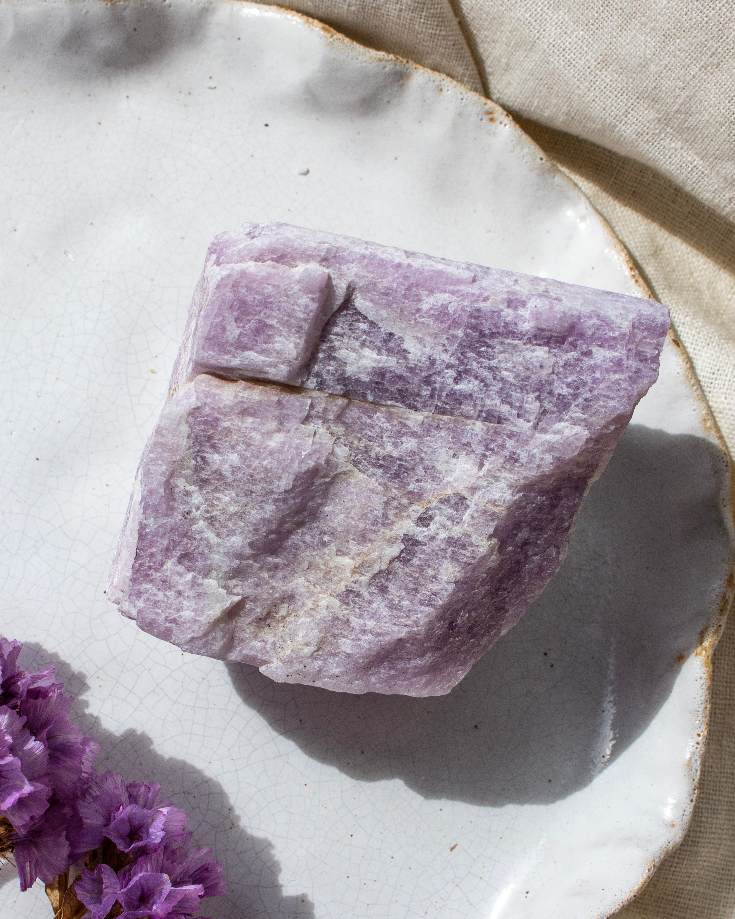 Purple crystal on a white ceramic plate with purple flowers