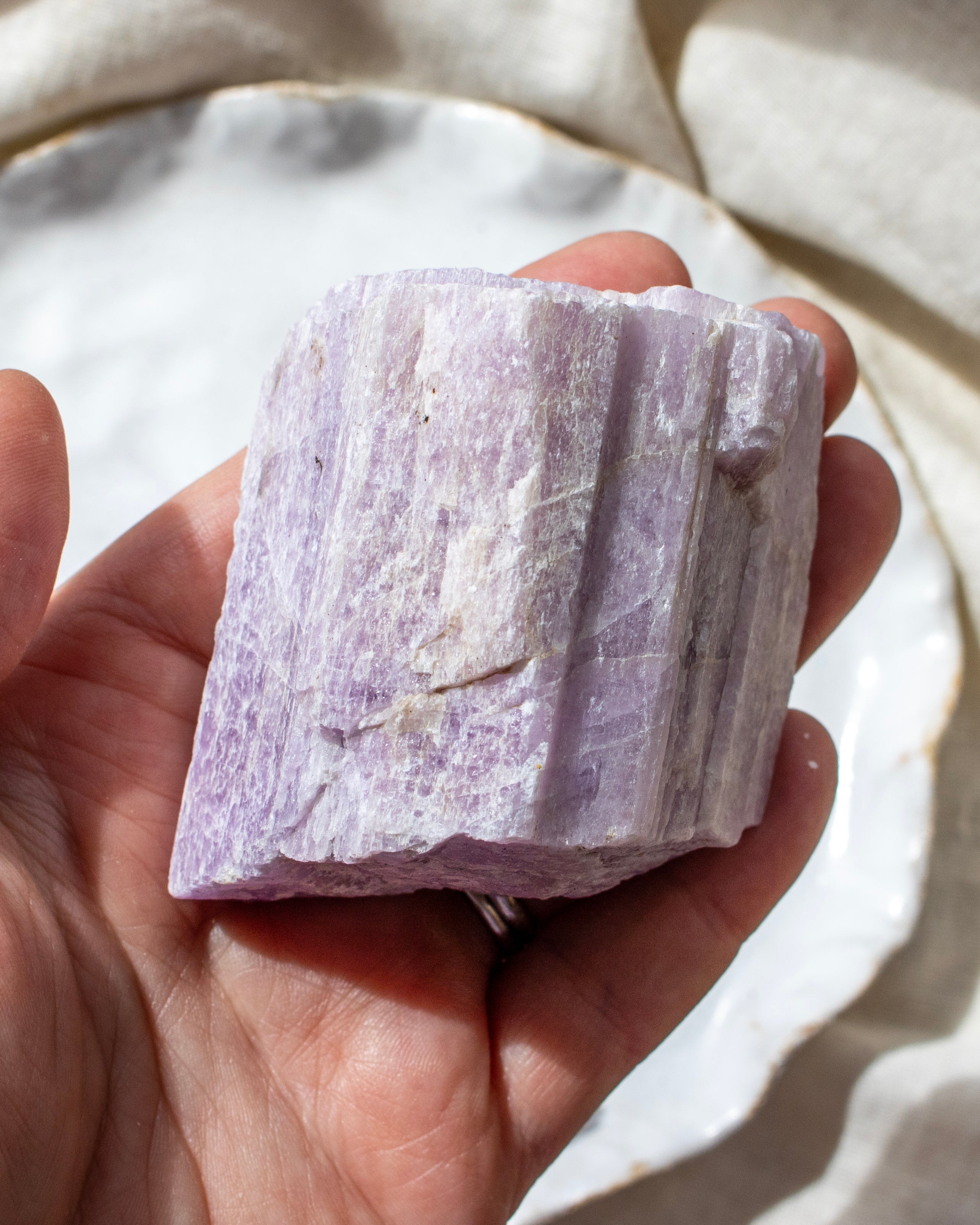 Hand holding a large purple crystal block against a neutral background