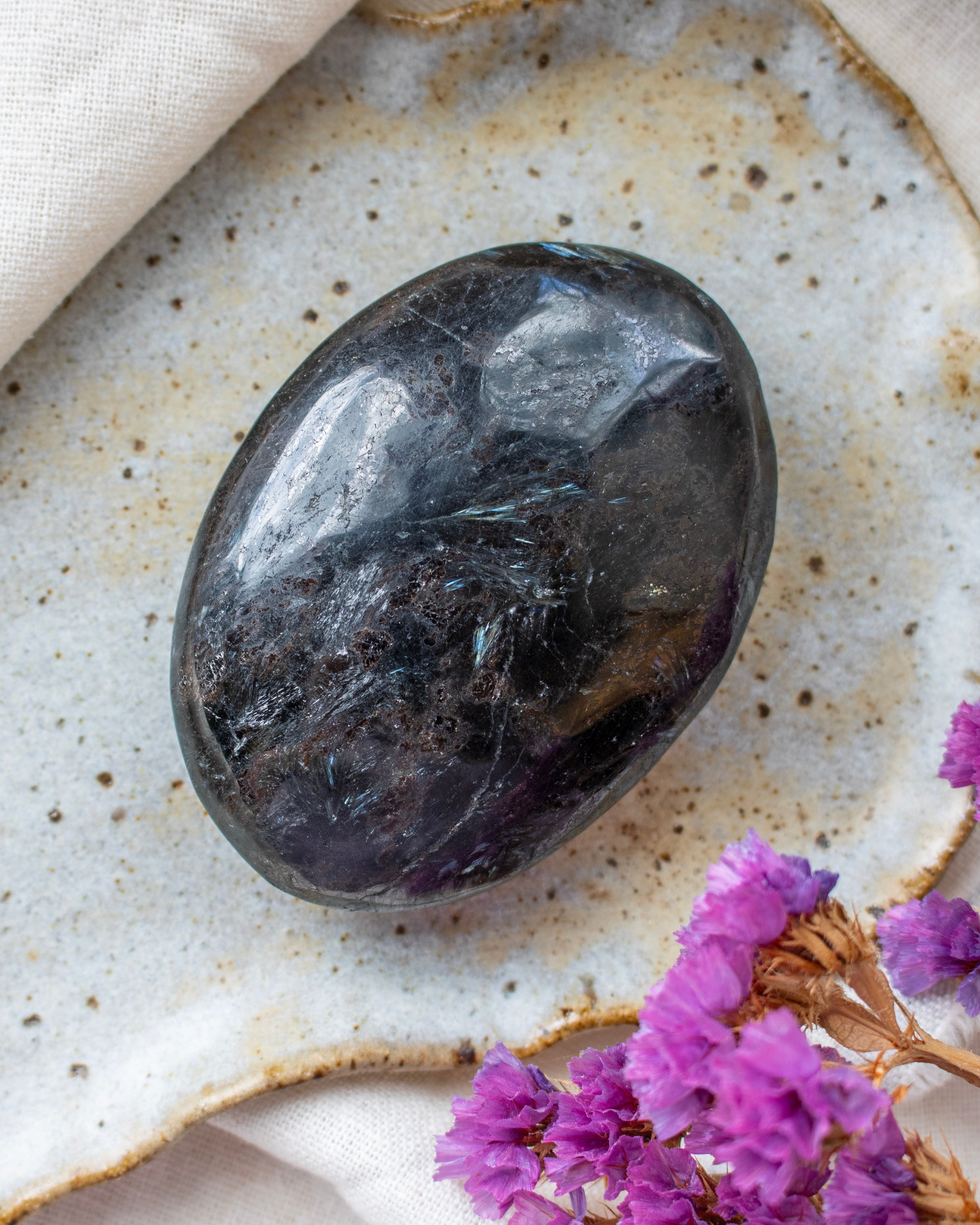 Black stone on a textured surface with purple flowers