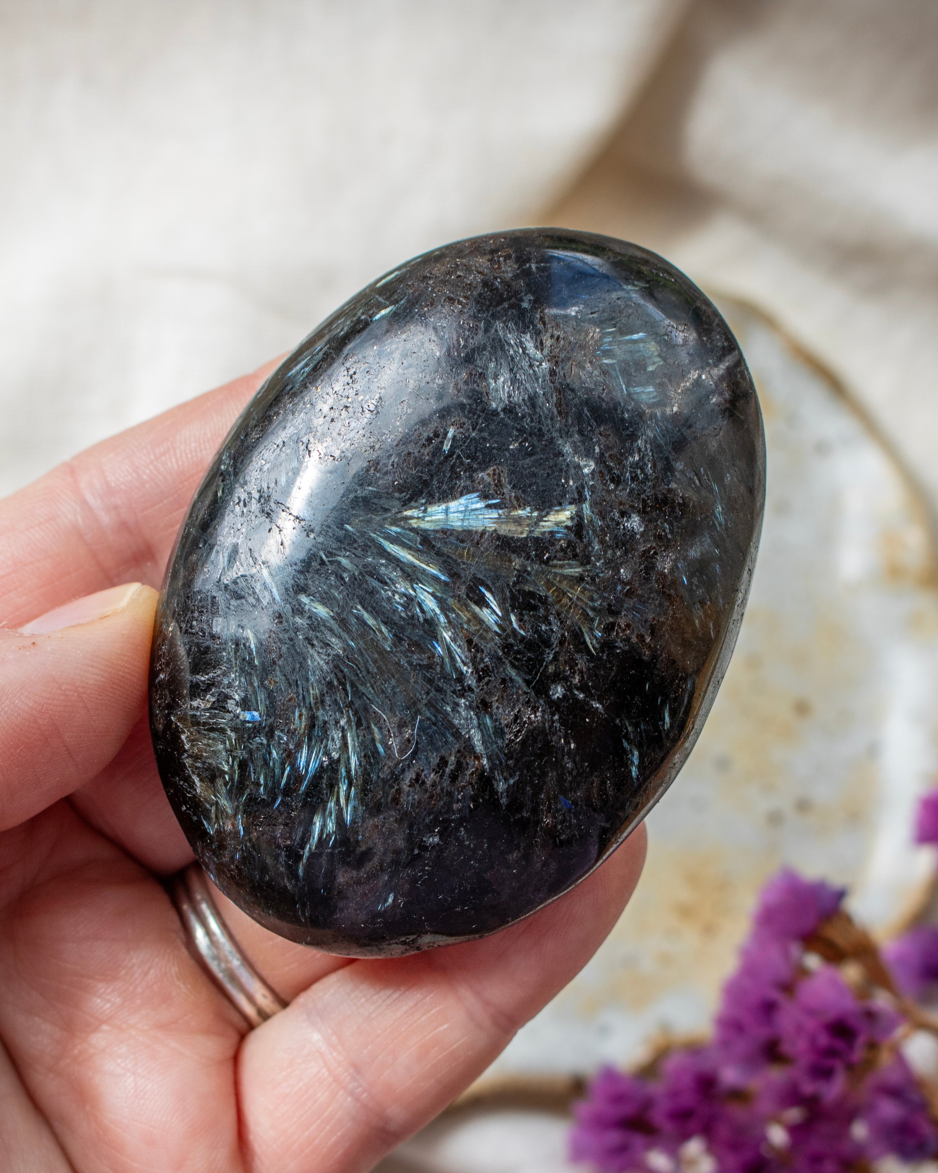 Person holding a dark crystal stone with a blurred background