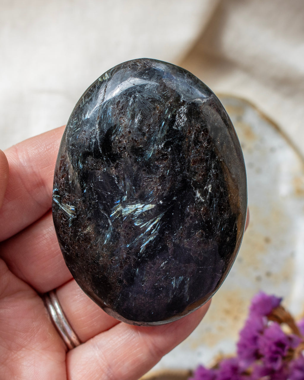 Oval-shaped black stone held in a hand with a blurred background