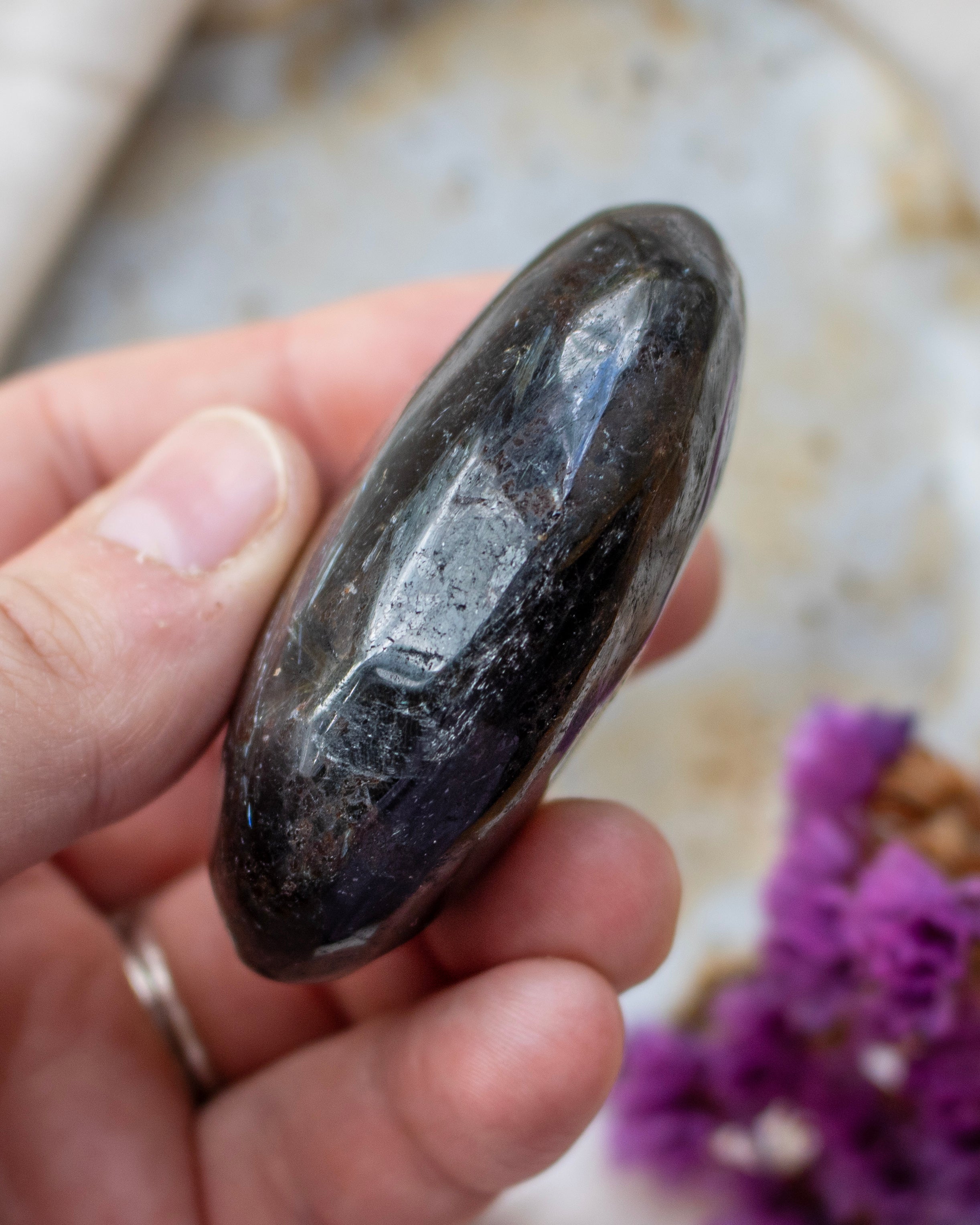 Hand holding a dark crystal with a blurred background