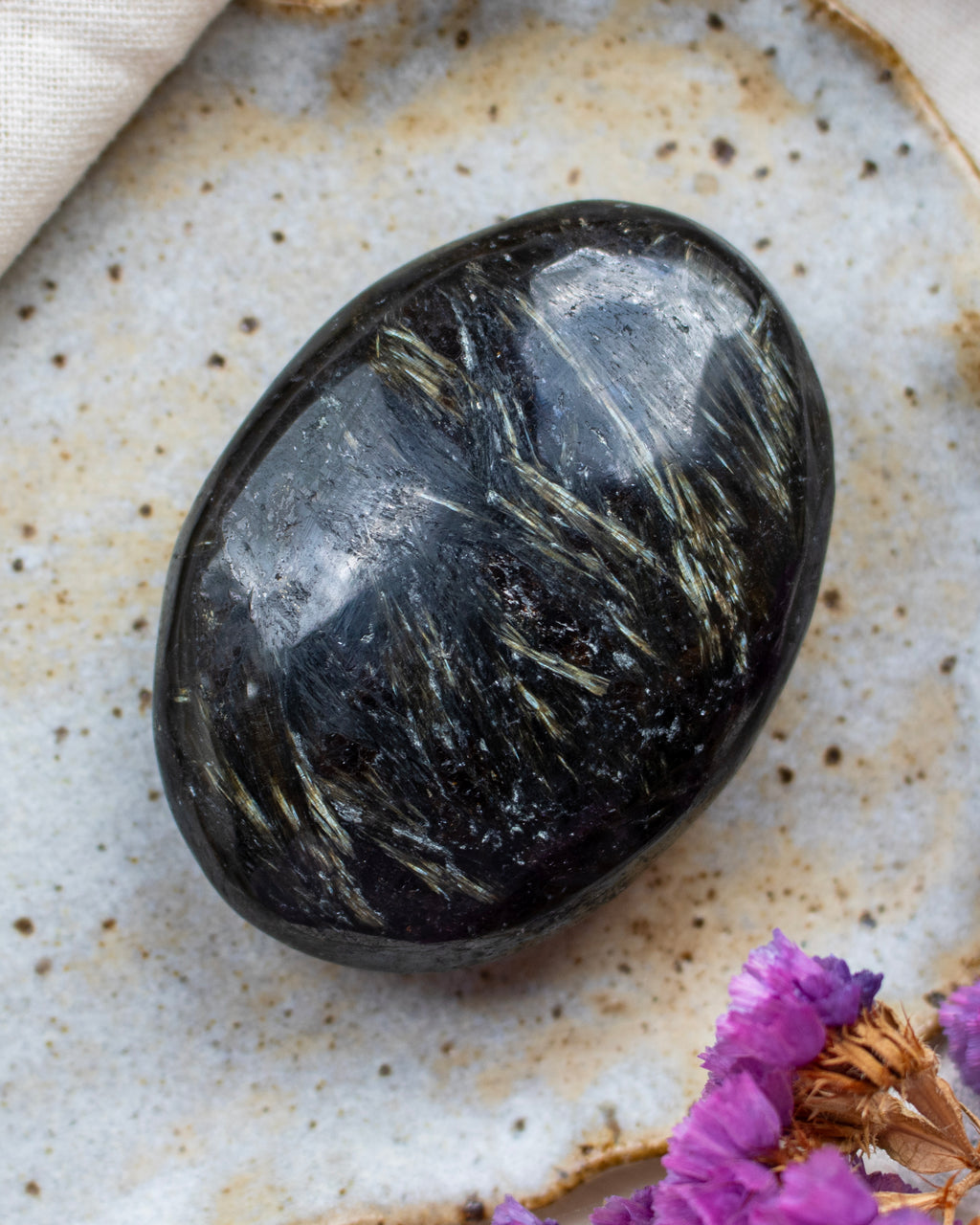 Black stone on a textured surface with purple flowers