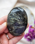 Hand holding a polished crystal rock with a blurred background