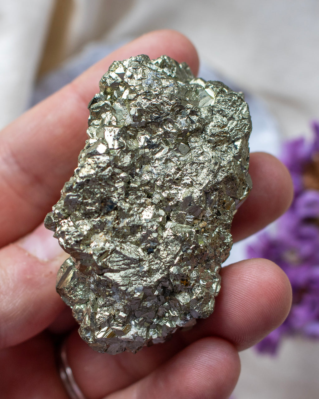 Hand holding a large pyrite crystal with a blurred background