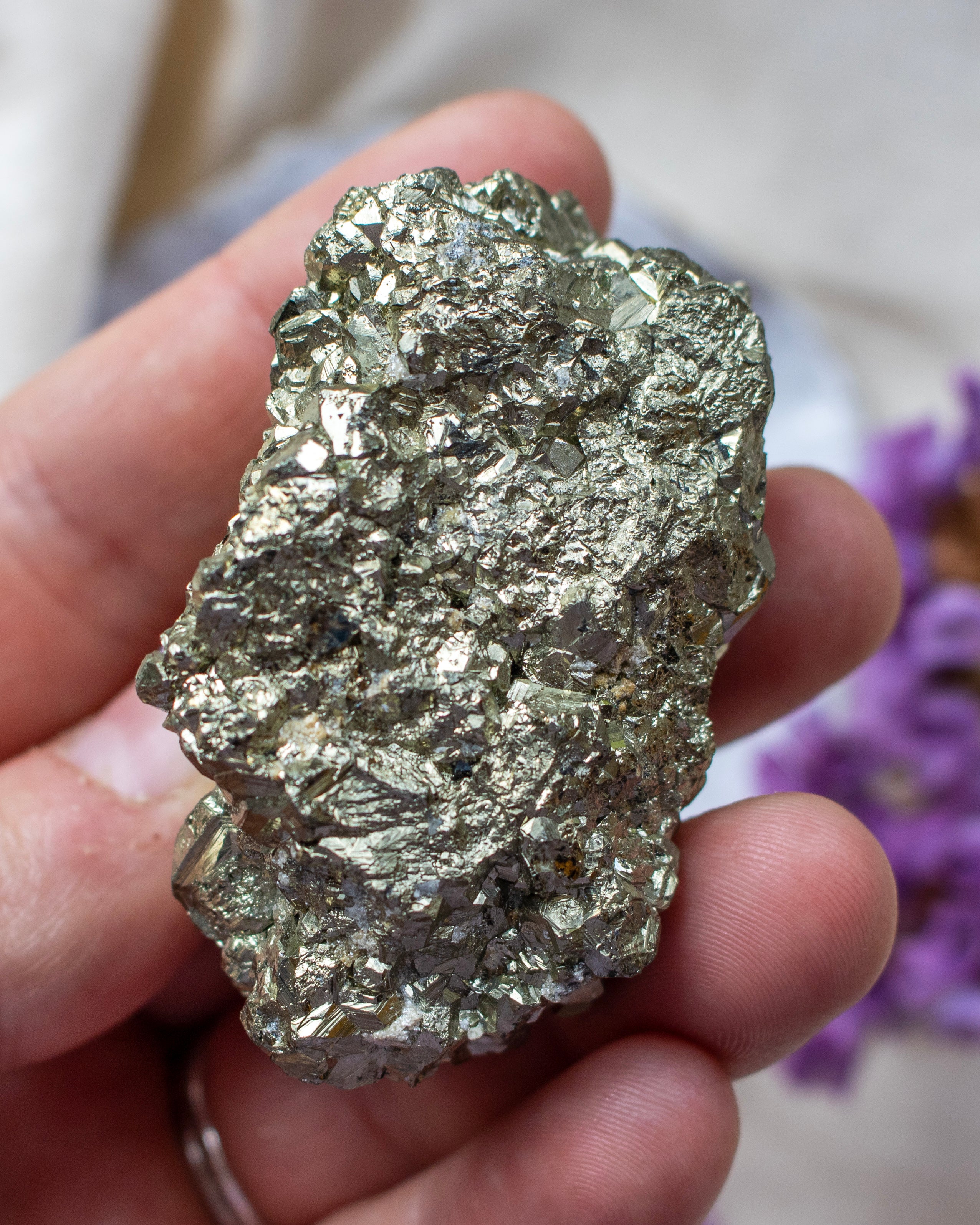 Hand holding a large pyrite crystal with a blurred background