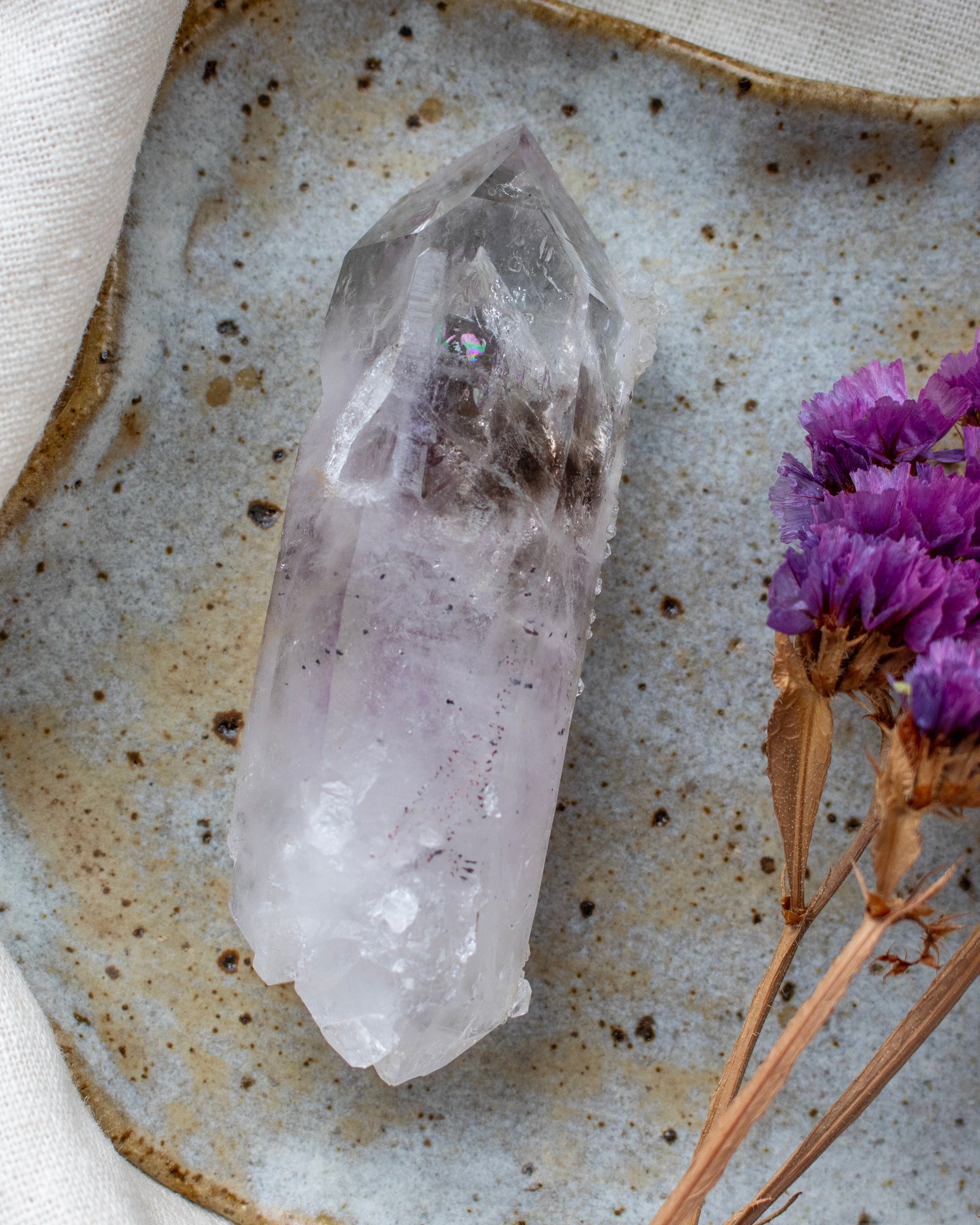 Crystal on a textured surface with purple flowers