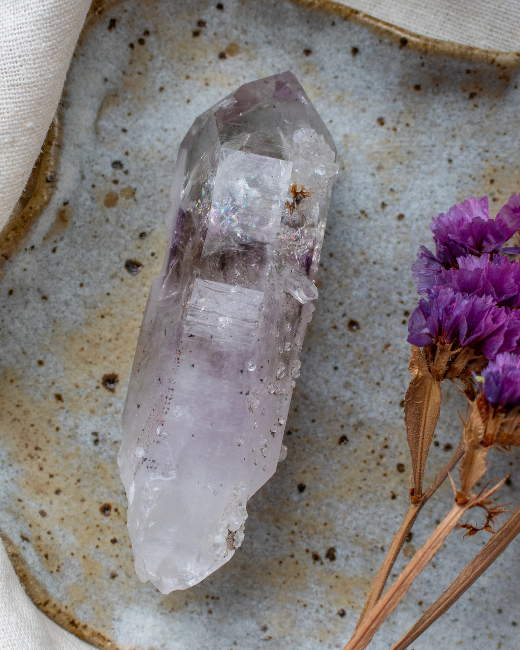 Crystal on a textured surface with purple flowers