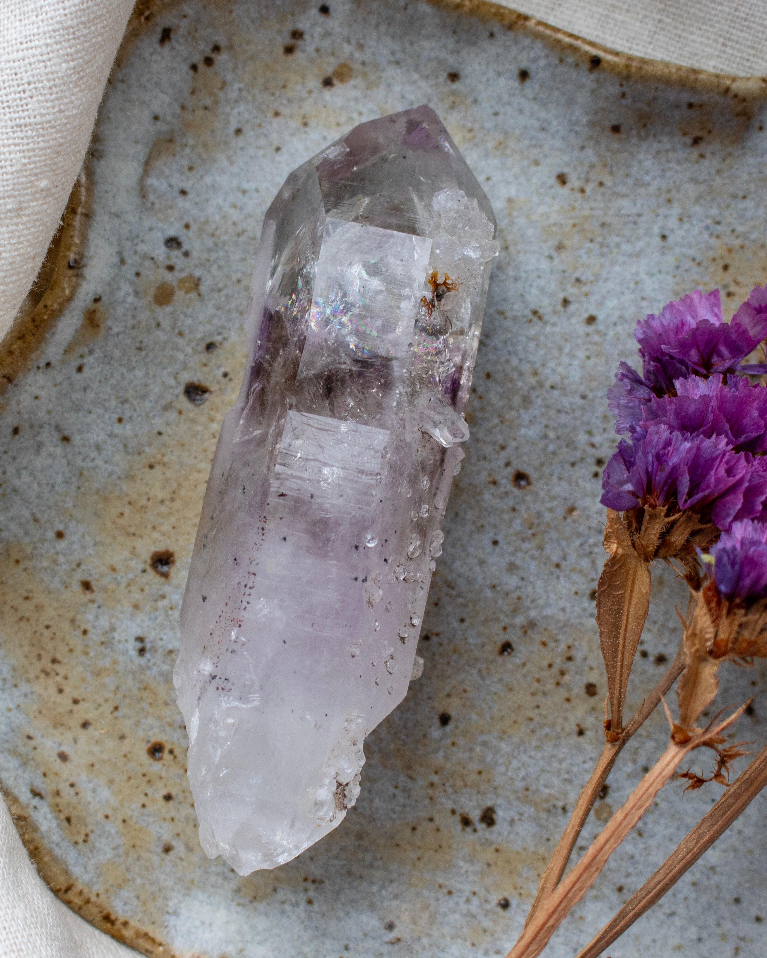 Crystal on a textured surface with purple flowers