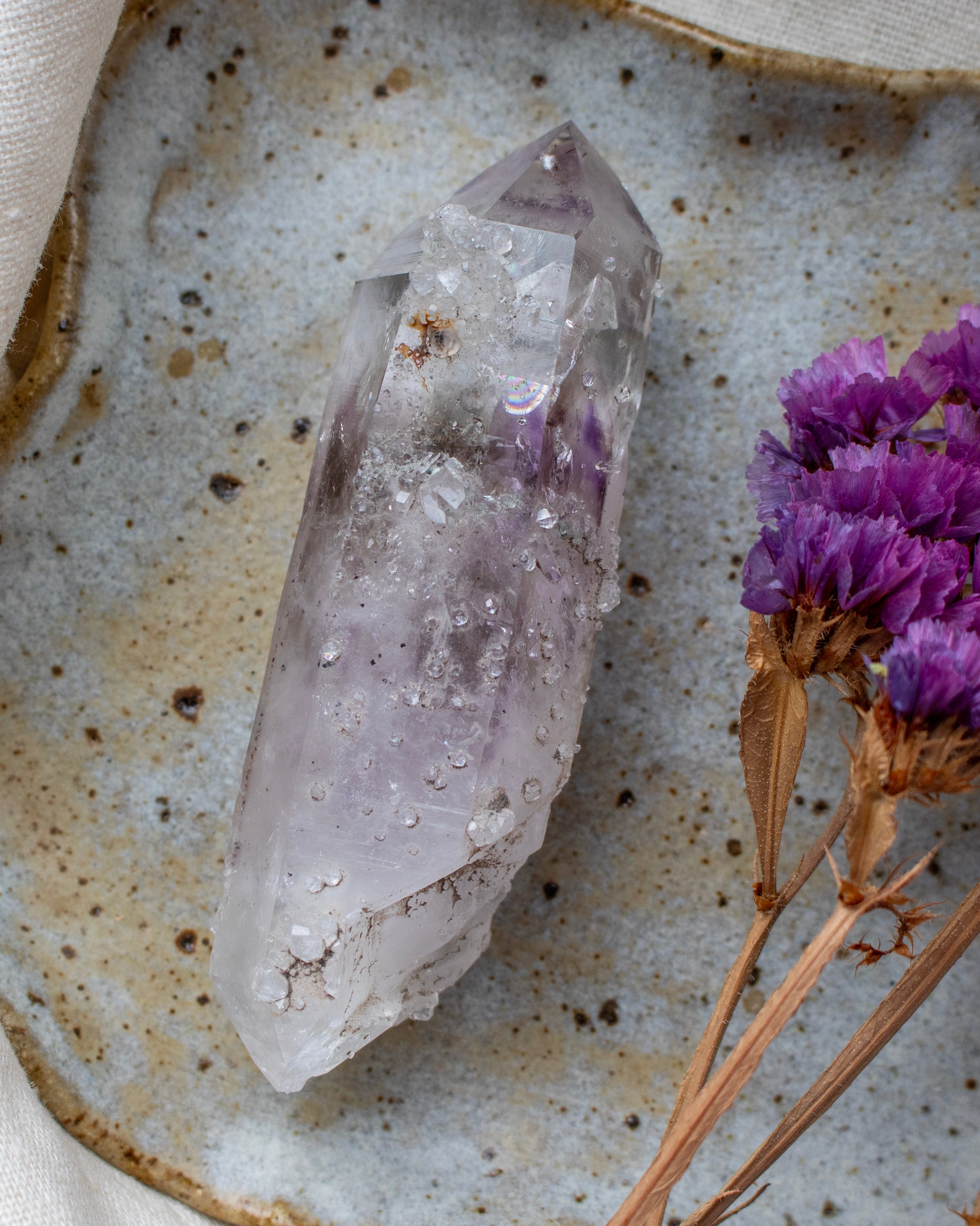 Crystal on a textured surface with purple flowers