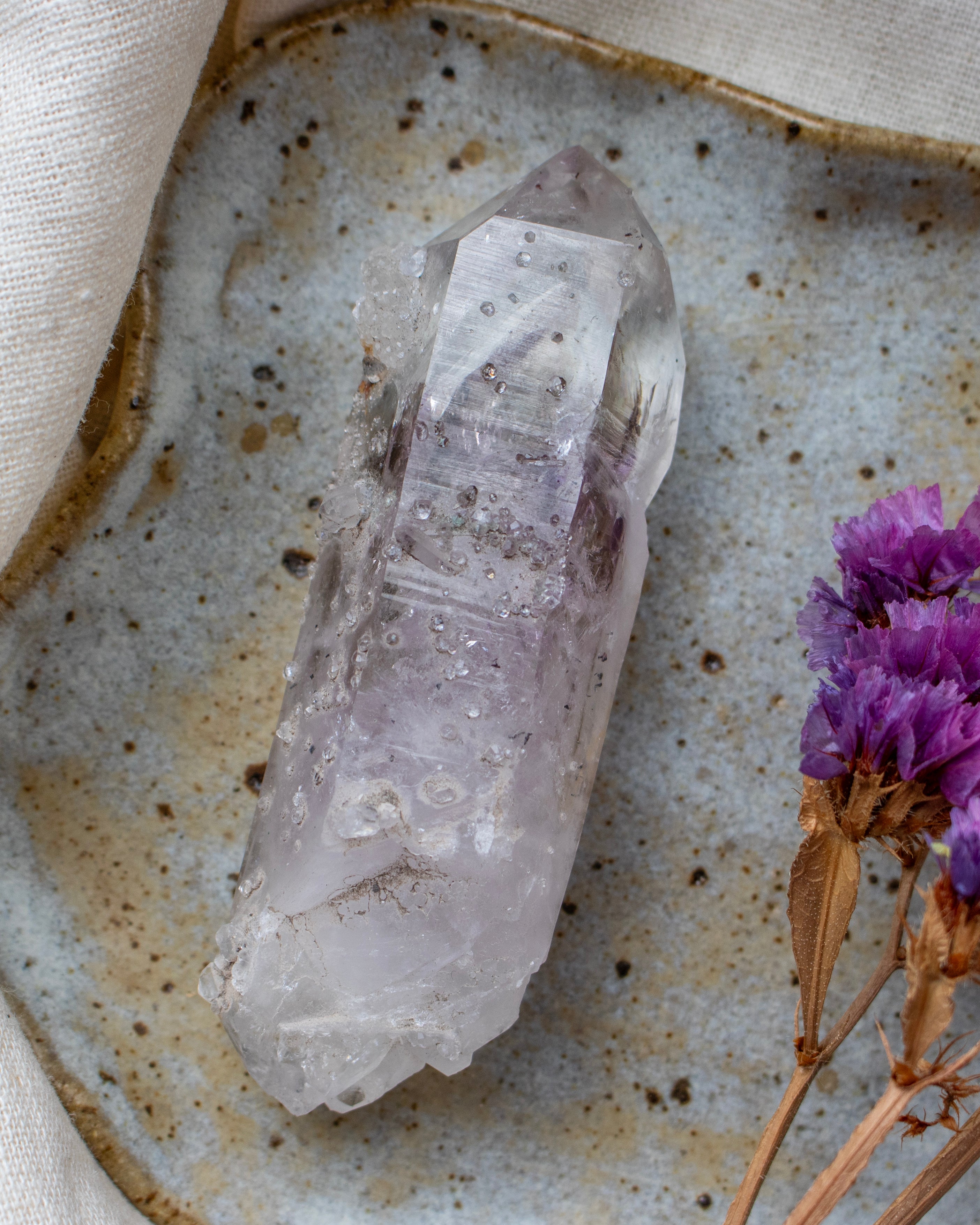 Clear crystal on a textured ceramic plate with purple flowers