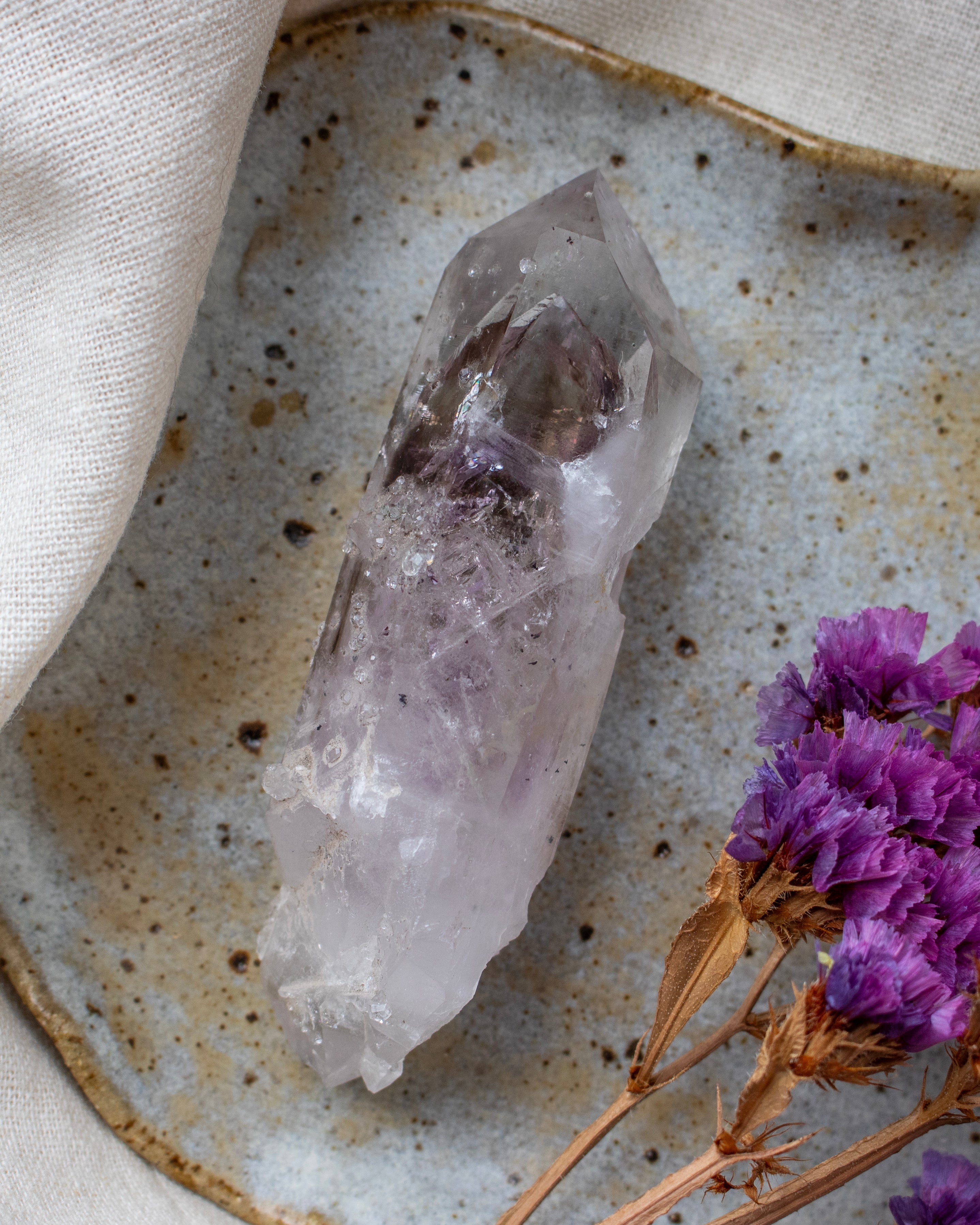 Crystal on a textured surface with purple flowers