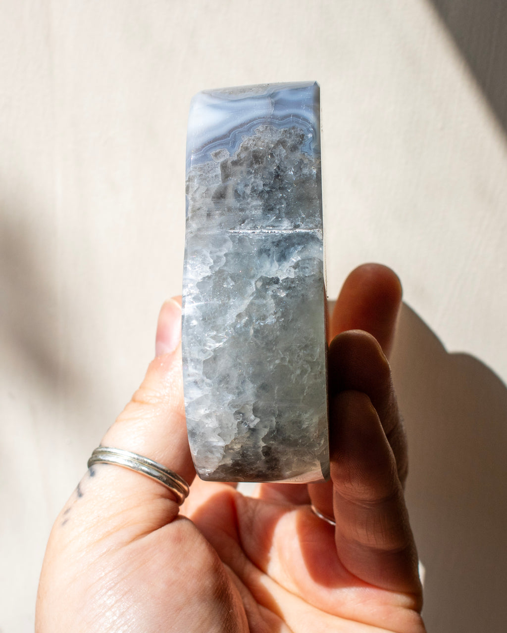 Hand holding a large blue and gray marbled stone against a neutral background
