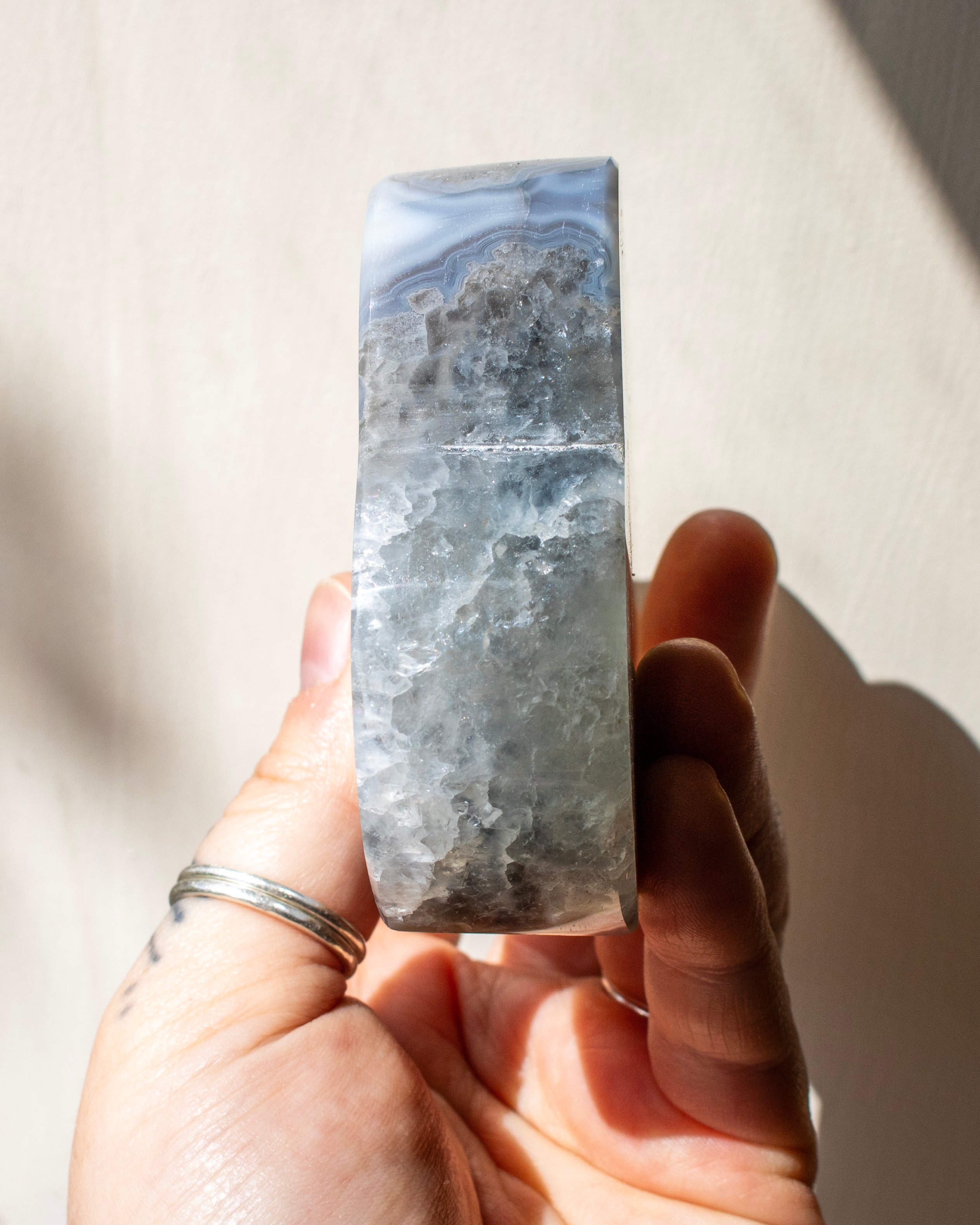 Hand holding a large blue and gray marbled stone against a neutral background