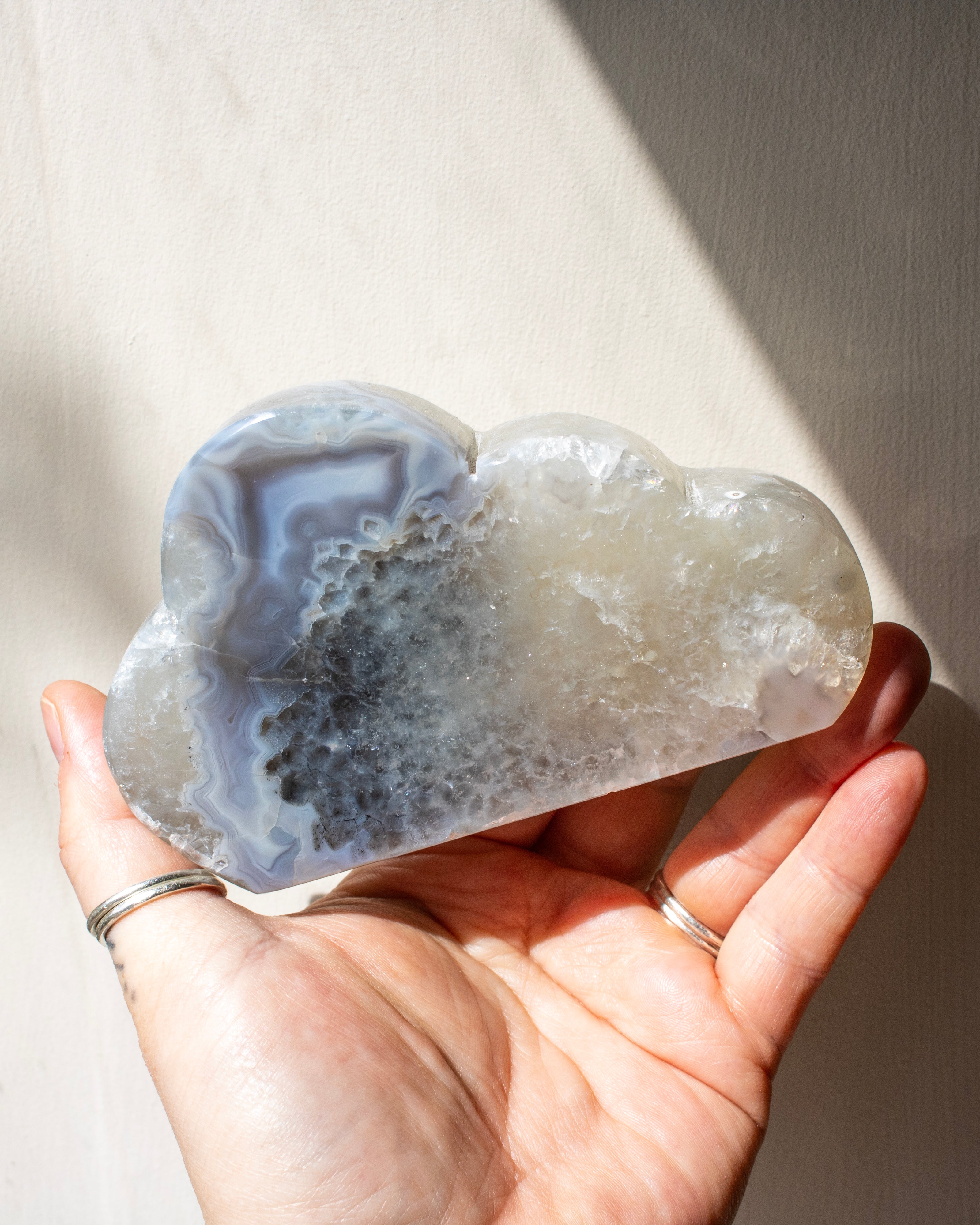 Cloud-shaped crystal held in a hand with a neutral background