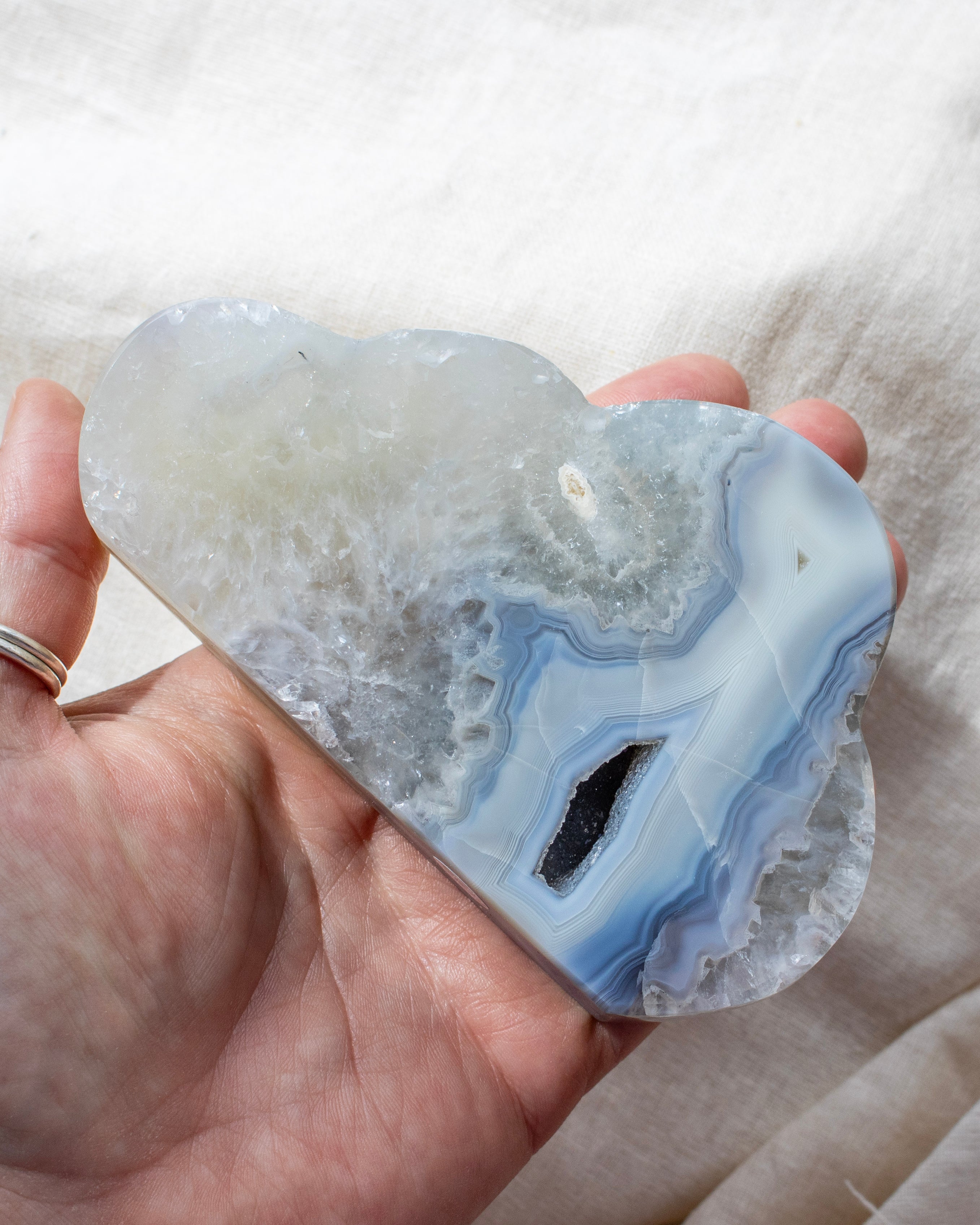 Cloud-shaped geode held in a hand against a neutral background