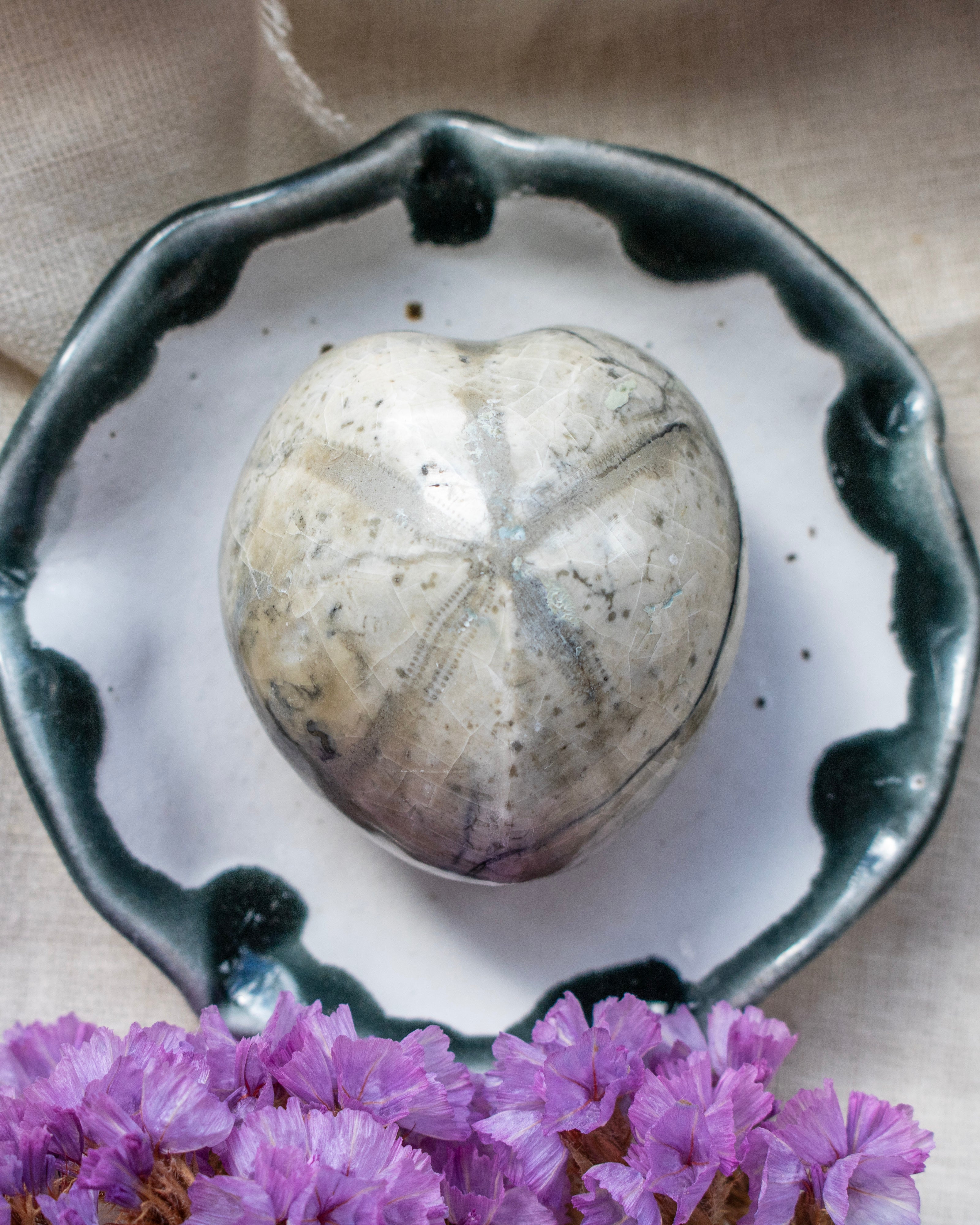 Decorative stone on a ceramic plate with purple flowers in the foreground