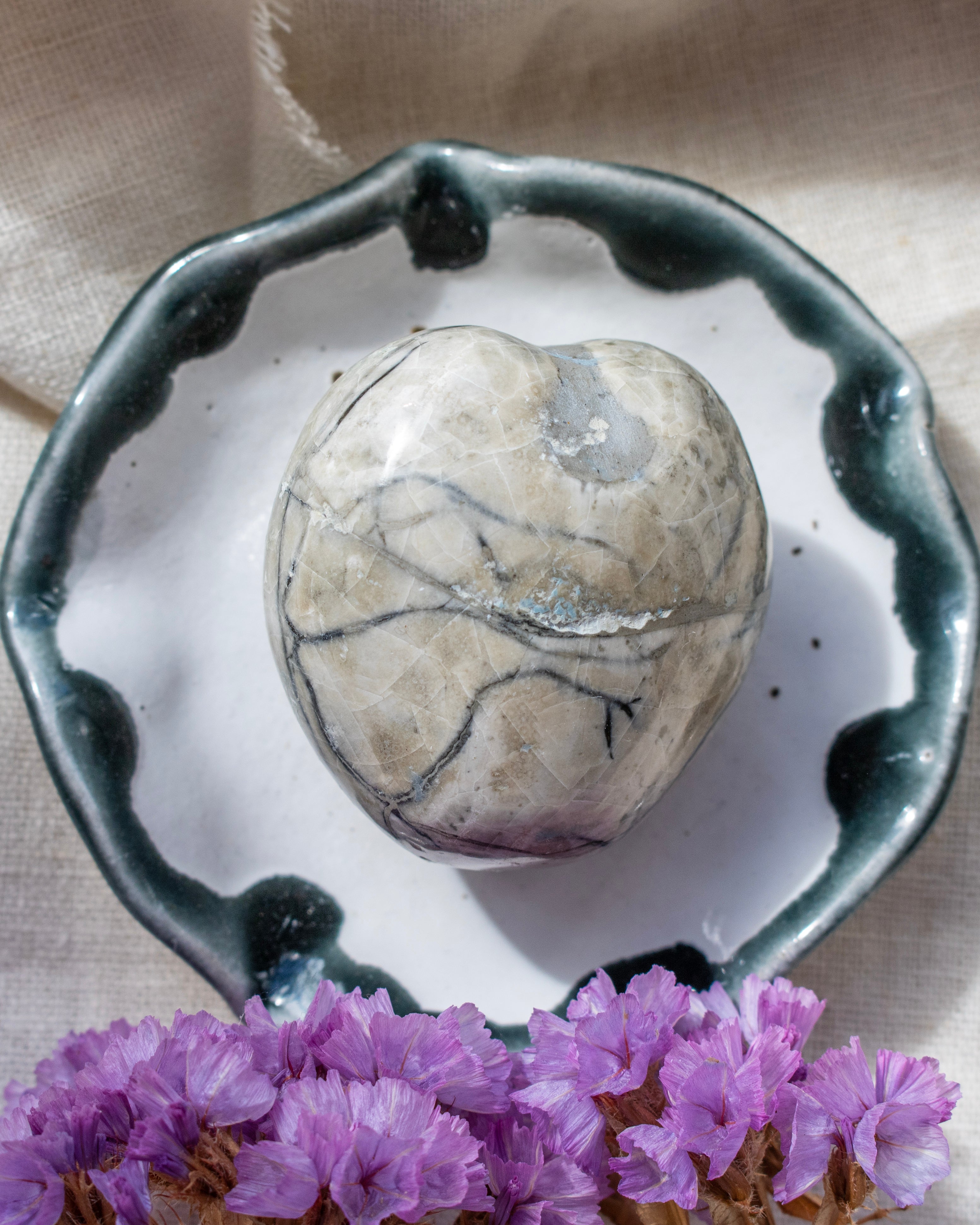 Marble-patterned stone on a ceramic dish with purple flowers in the foreground