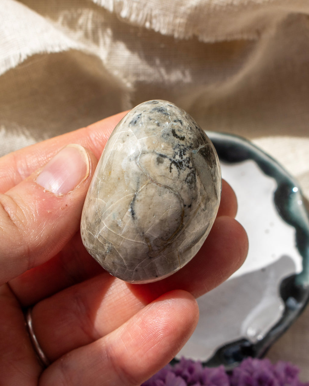 Hand holding a marbled stone with a neutral background