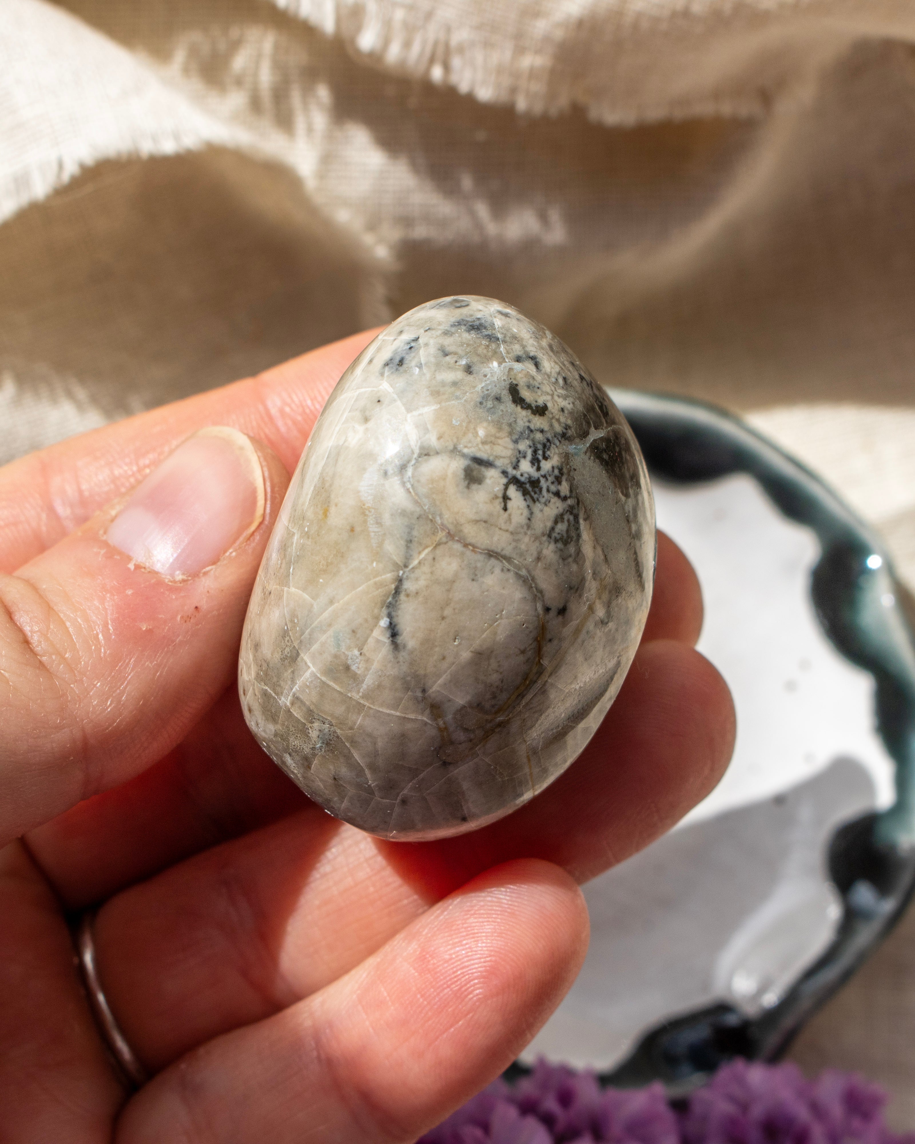 Hand holding a marbled stone with a neutral background