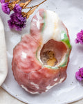 Decorative stone with a central cavity on a white plate with purple flowers.