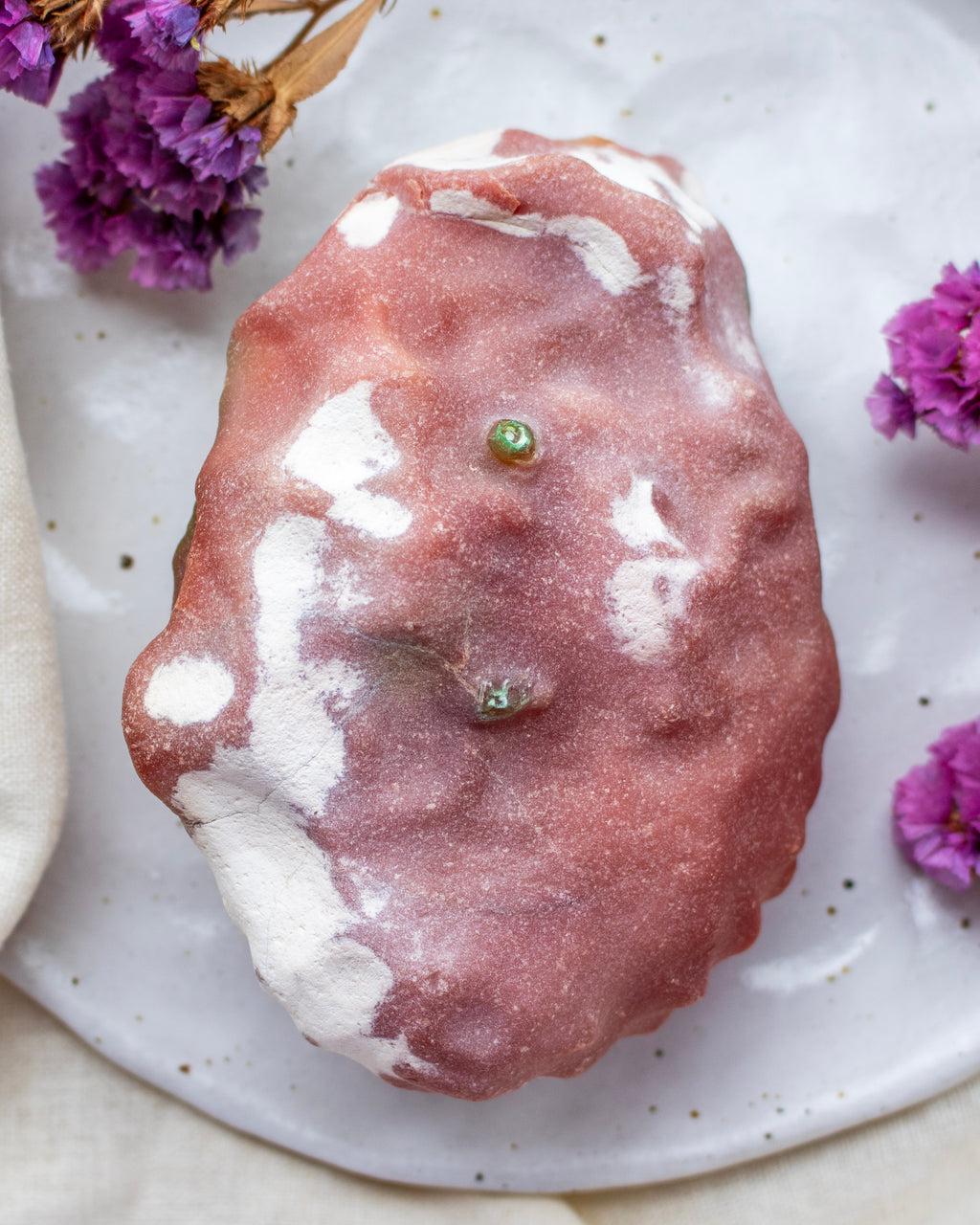 Pink stone on a speckled plate with purple flowers
