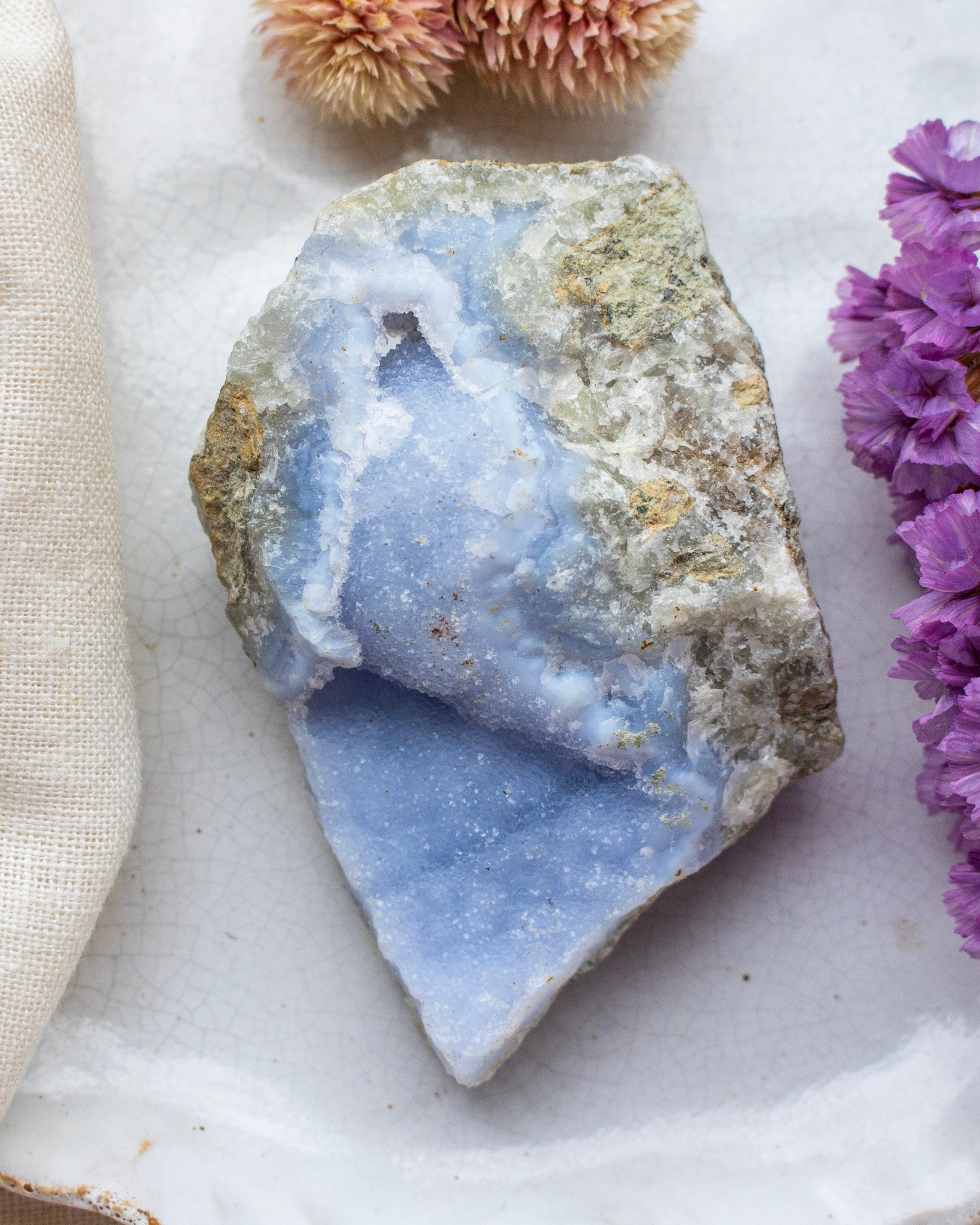 Geode crystal with purple flowers on a marble surface