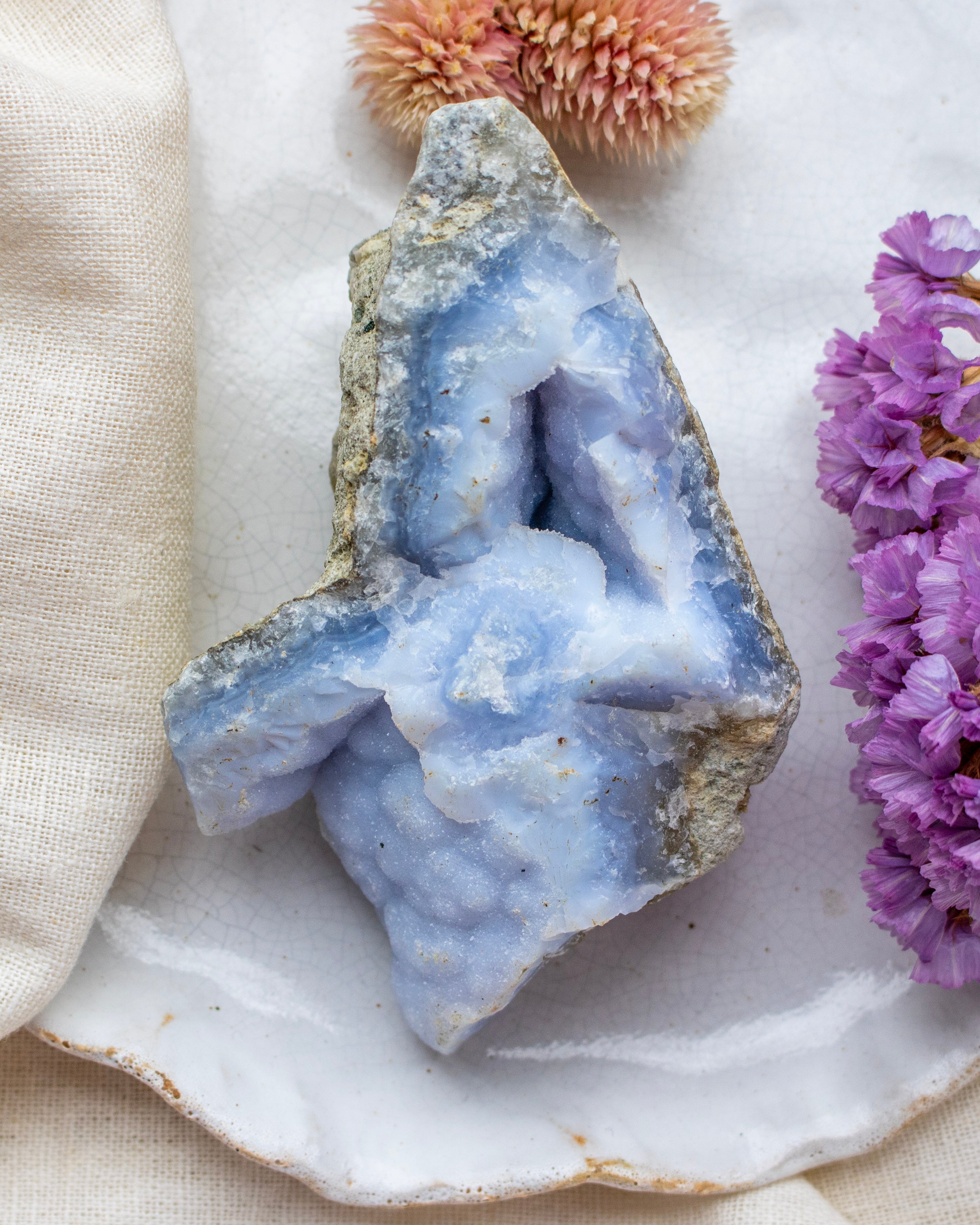 Geode crystal with purple flowers on a white surface