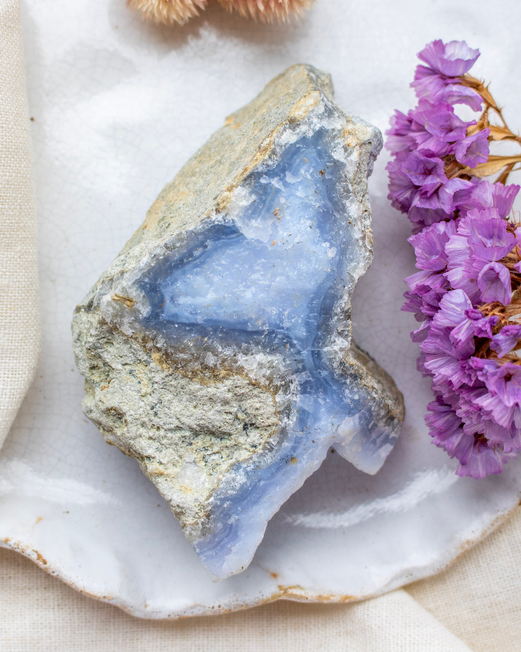 Geode crystal with purple flowers on a white surface
