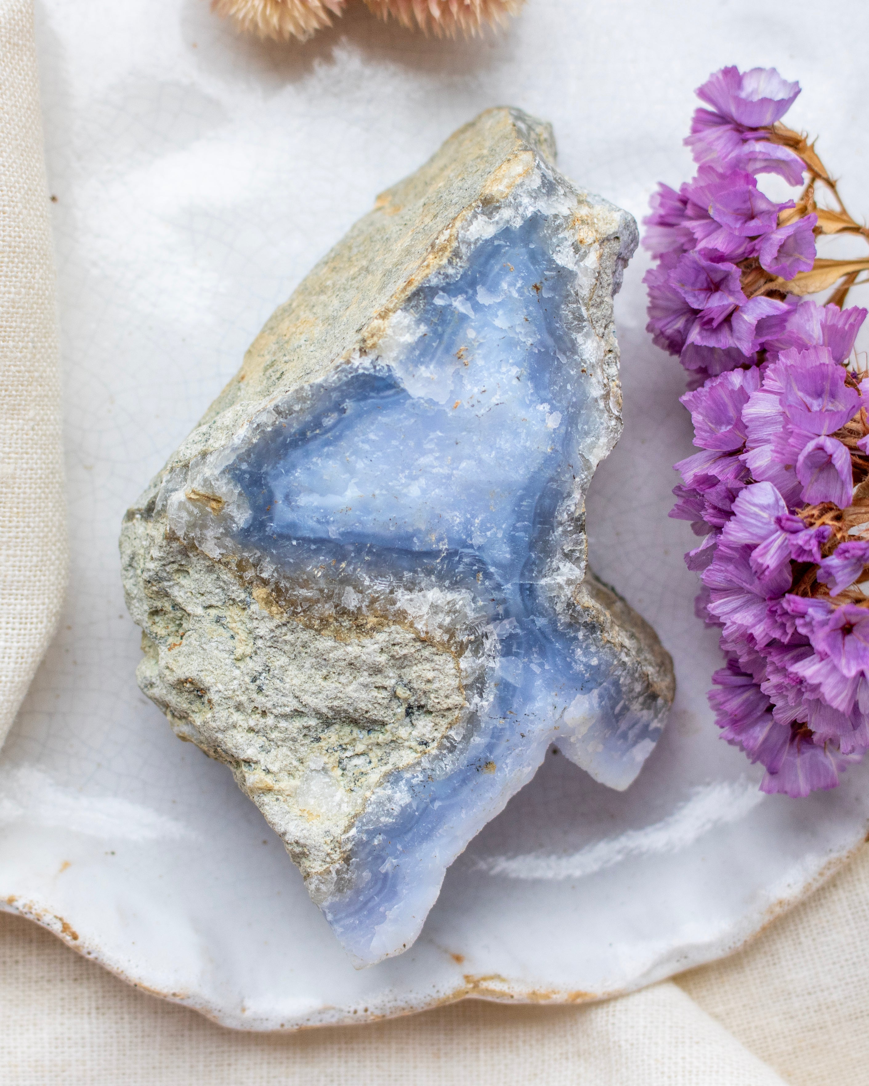 Geode crystal with purple flowers on a white surface