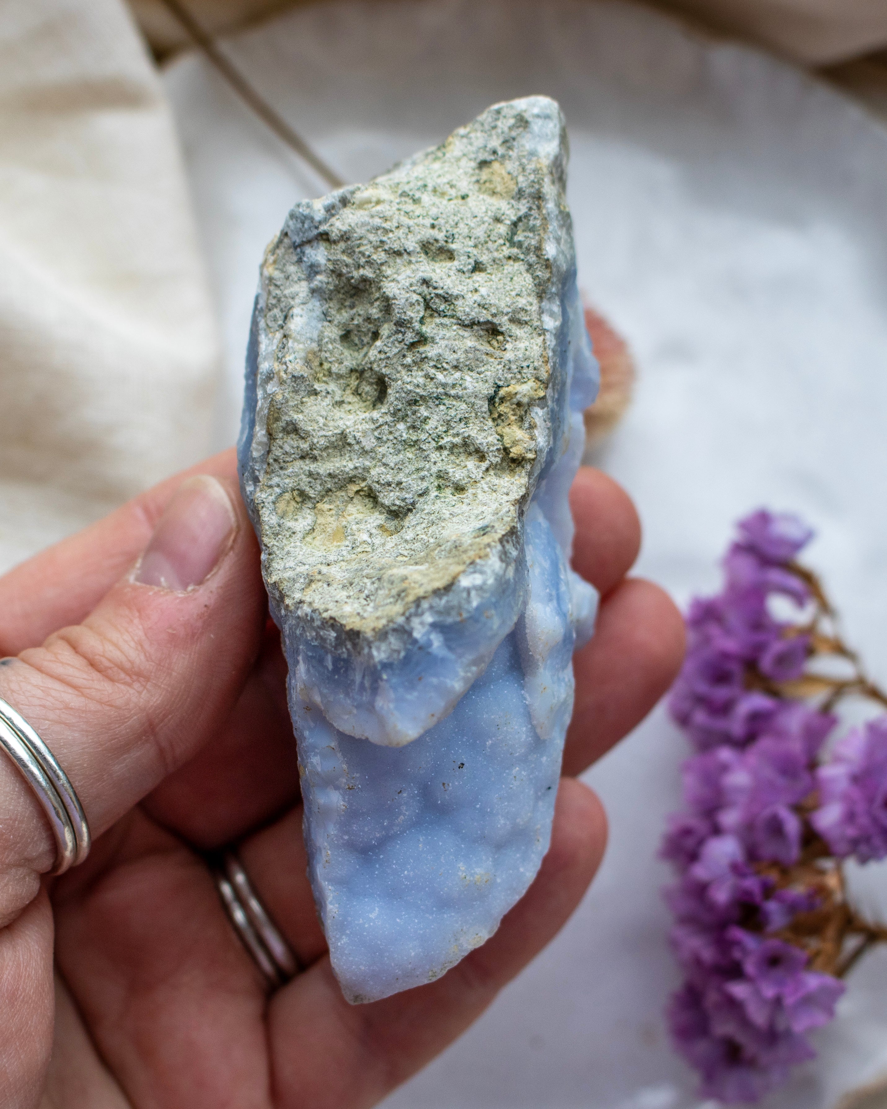 Hand holding a rough crystal rock with a blurred background