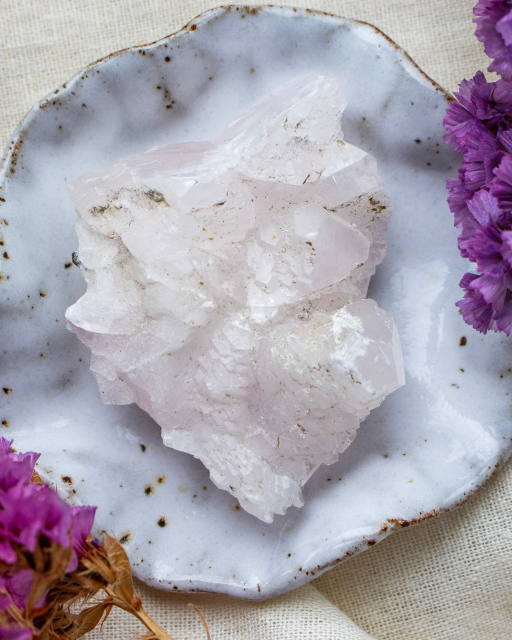 Crystal rock on a textured white plate with purple flowers